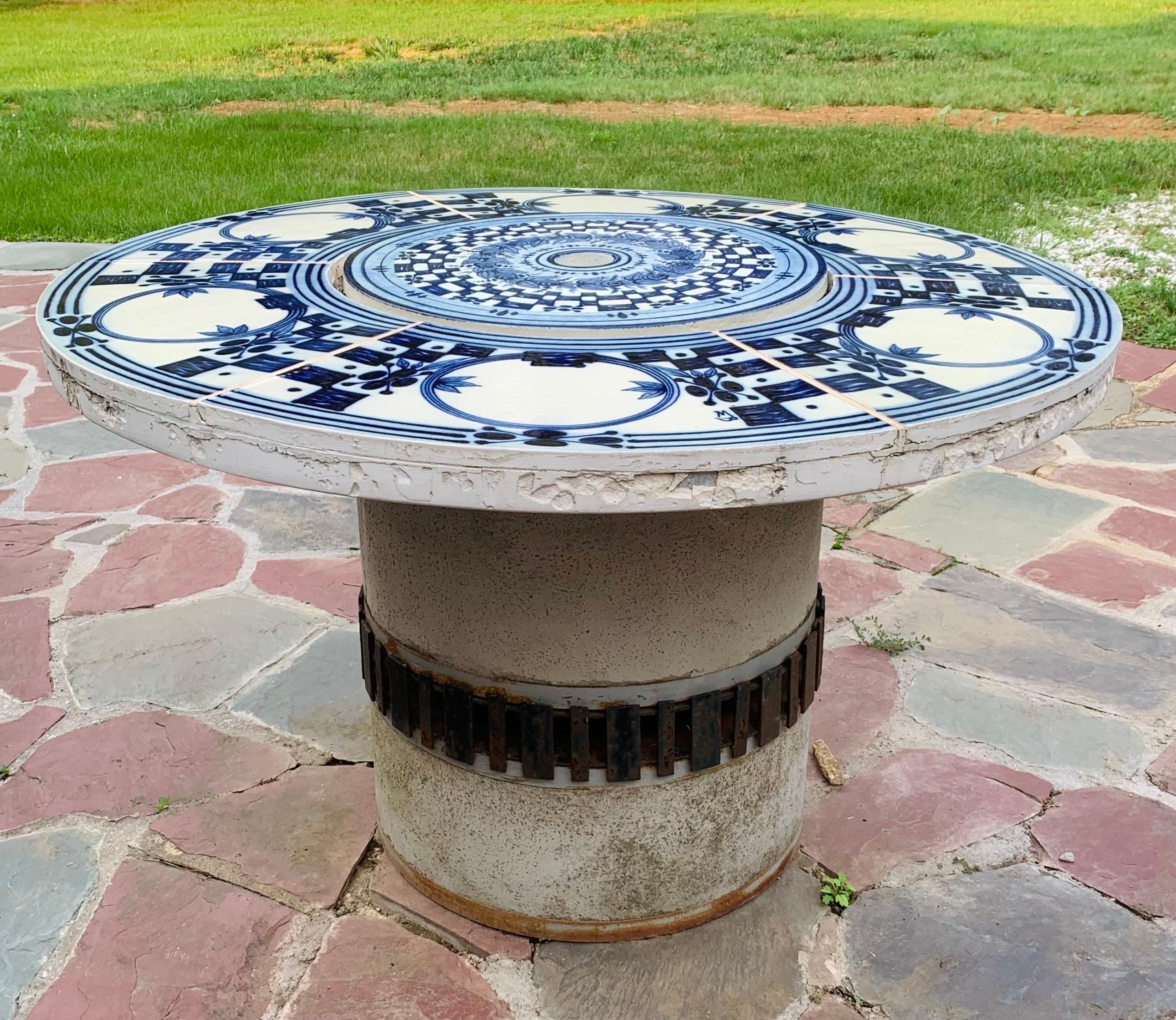 This is a large round outdoor Hibachi grilling table. Its top is paved with hand-painted blue and white faience tiles, and it has a cast concrete base.

The tiles were painted by artist Bjørn Wiinblad, an important Danish painter and