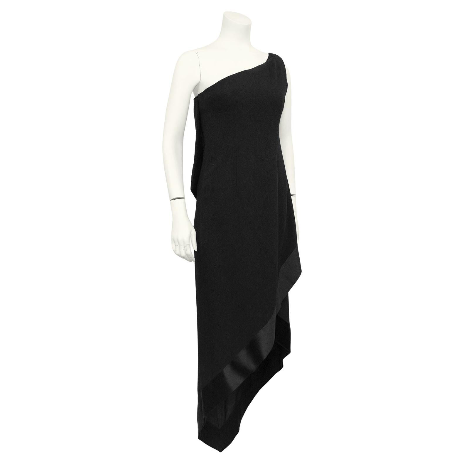 Épurée, structurée et d'une beauté sans effort, cette robe du soir à une épaule de Christian Dior, datant de 1968, résiste à l'épreuve du temps. Fabriquée en crêpe de laine noire avec une bordure de satin noir de 3 pouces d'épaisseur, la robe a été