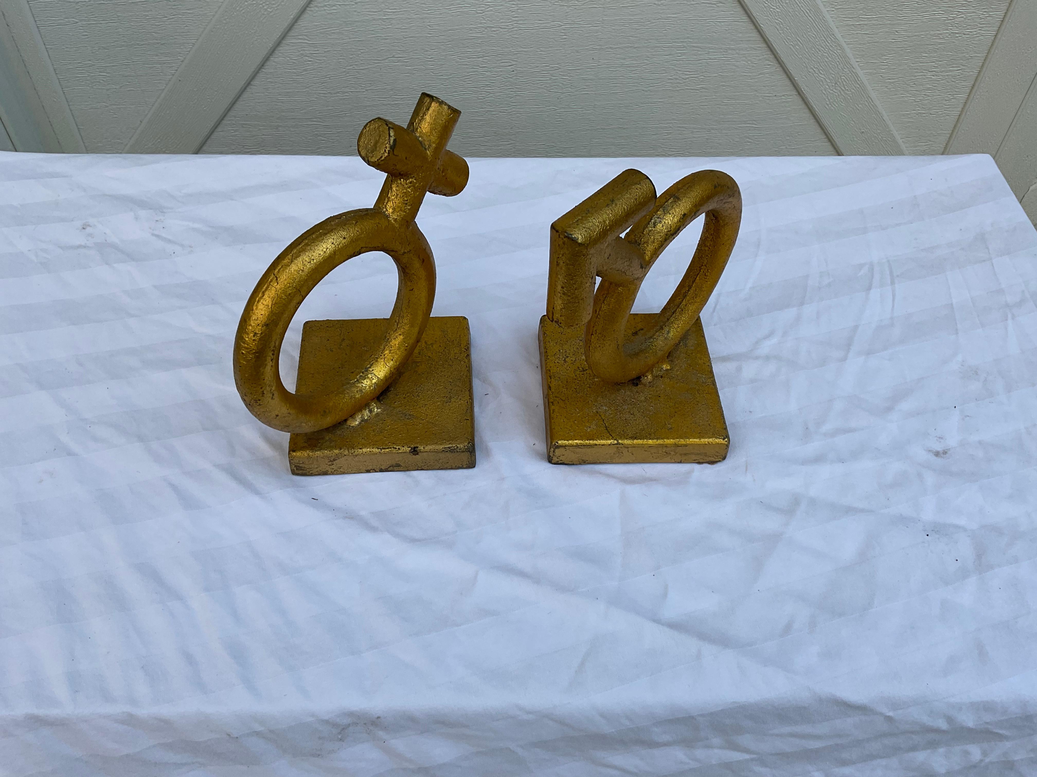 Classic pair of gilt iron bookends, signed C Jere, 1968. One, the sign for female, and one, the sign for male. Heavy enough to actually hold books, or just use, decoratively.