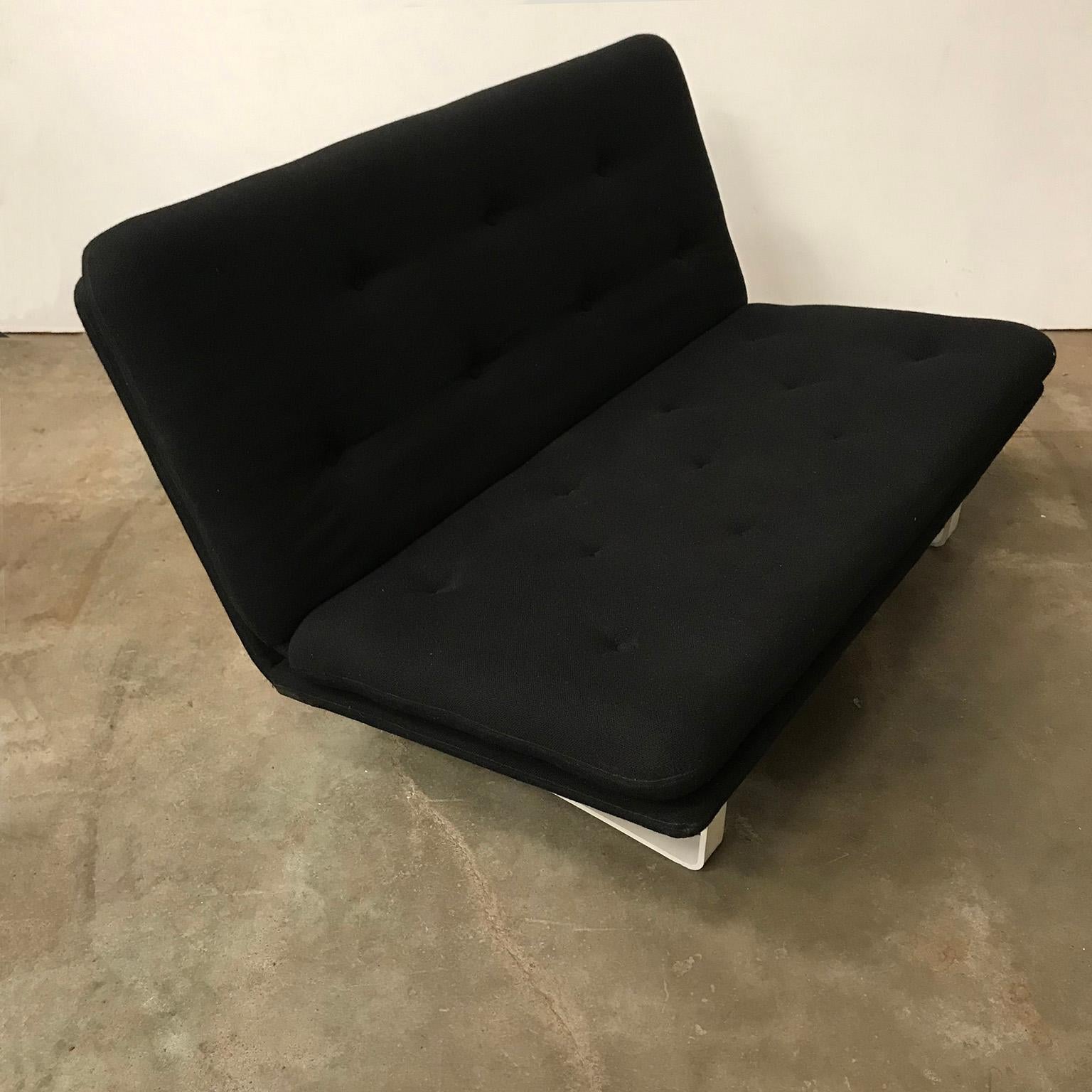Original, early, stronger manufactured as nowadays, Kho Liang Ie sofa two-seat, not in production anymore, in black fabric and padded. The upholstery shows some traces of wear like some fading of the colour and some pilling. The legs are white and