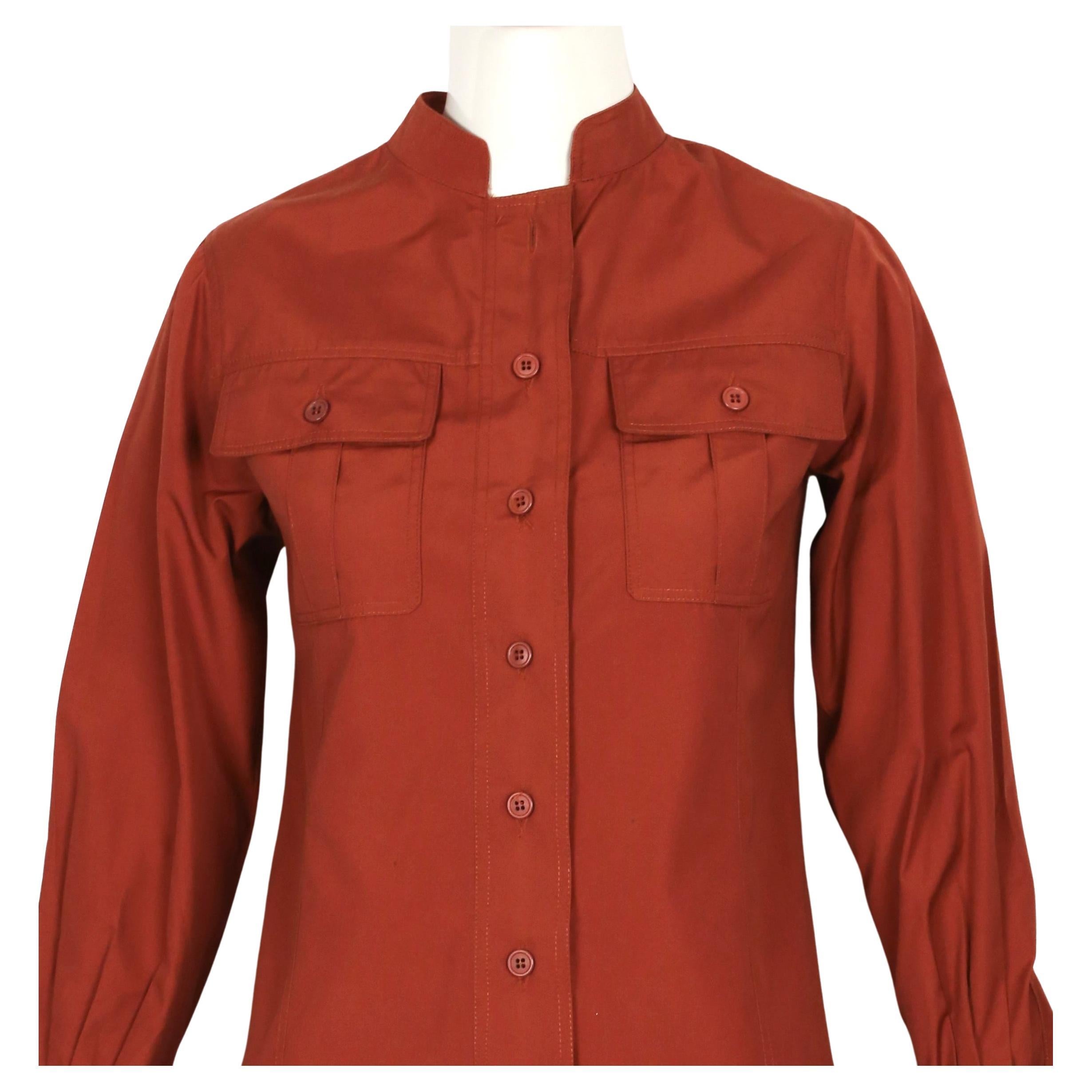 Extremely rare, rust 'saharienne' safari tunic from Yves Saint Laurent dating to 1968 as seen on Yves Saint Laurent in London. This is a very well documented and historically significant Saint Laurent piece.  Tunic has a standing band collar and
