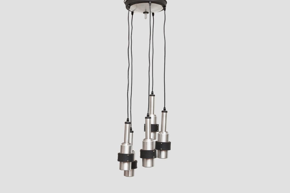 Lustre de 1968 par RAAK avec 5 lampes suspendues cylindriques en aluminium repoussé avec intérieur émaillé orange, détail de bande noire et grand baldaquin encastré à plusieurs abat-jours. En bon état d'origine avec une usure conforme à son âge et à