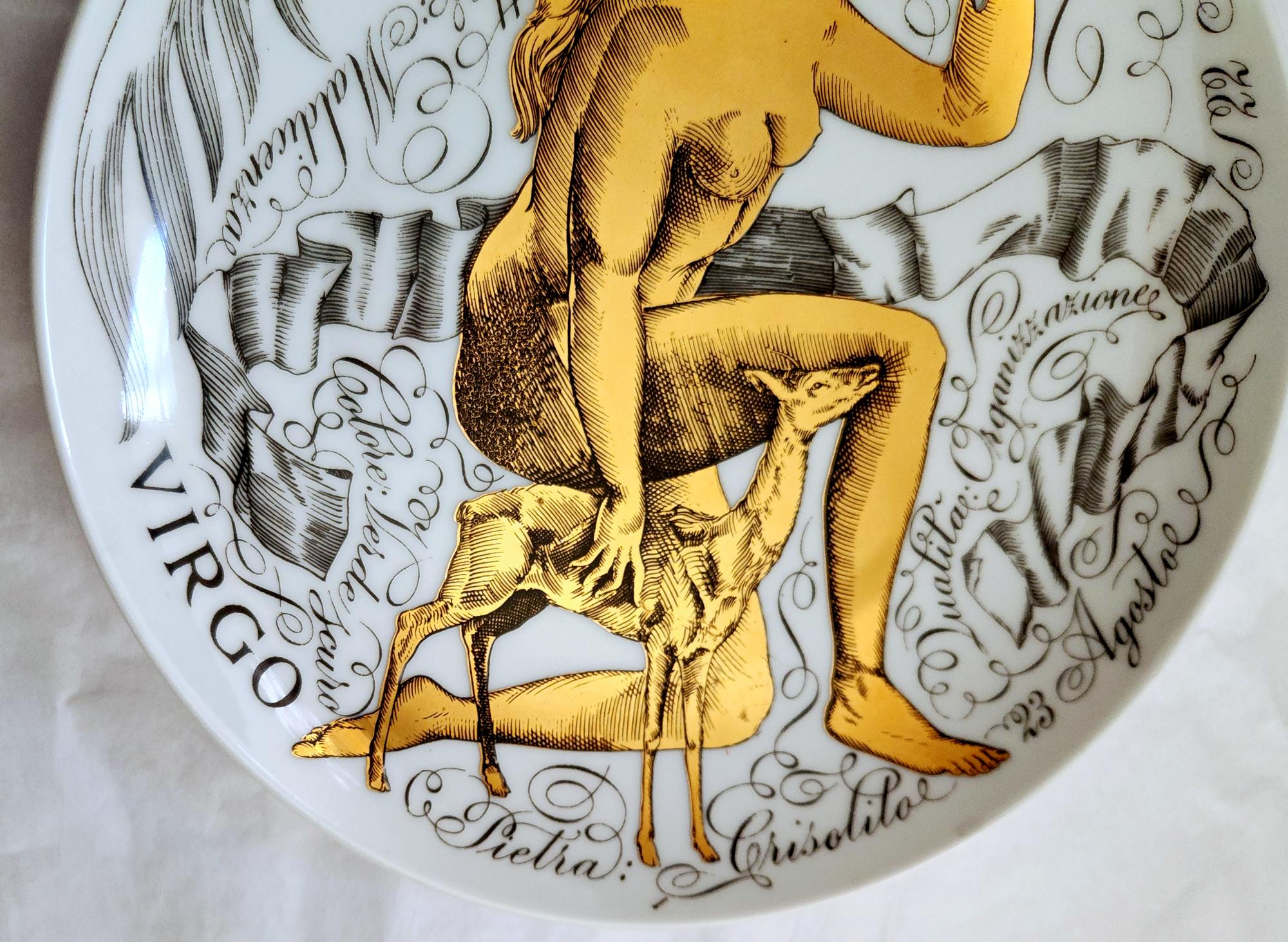 Piero Fornasetti Zodiac Porcelain Plate,
Virgo,
Made for Corisia in 1969 #6 in series.

The plate in black and gold depicts the astrological sign Virgo with words, intertwined around the form of a young naked woman kneeling by a fawn, with
