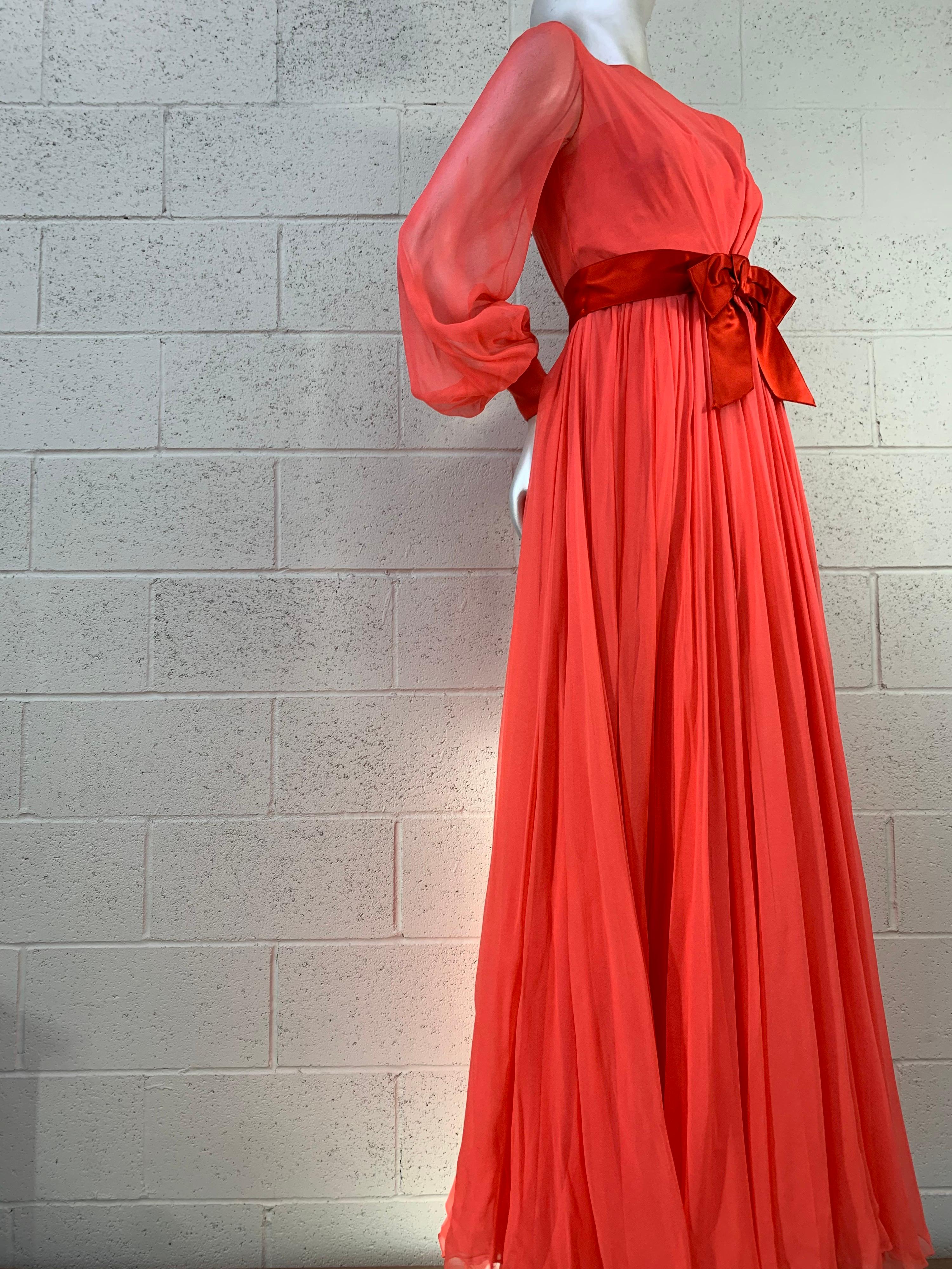 A gorgeous late 1960s Sarmi evening gown in two layers of deep coral silk chiffon with a wide silk satin sash at waist and cuffs. Beautiful sheer balloon sleeves and full sweeping skirt over a narrow chiffon and crepe sheath. Keyhole back with