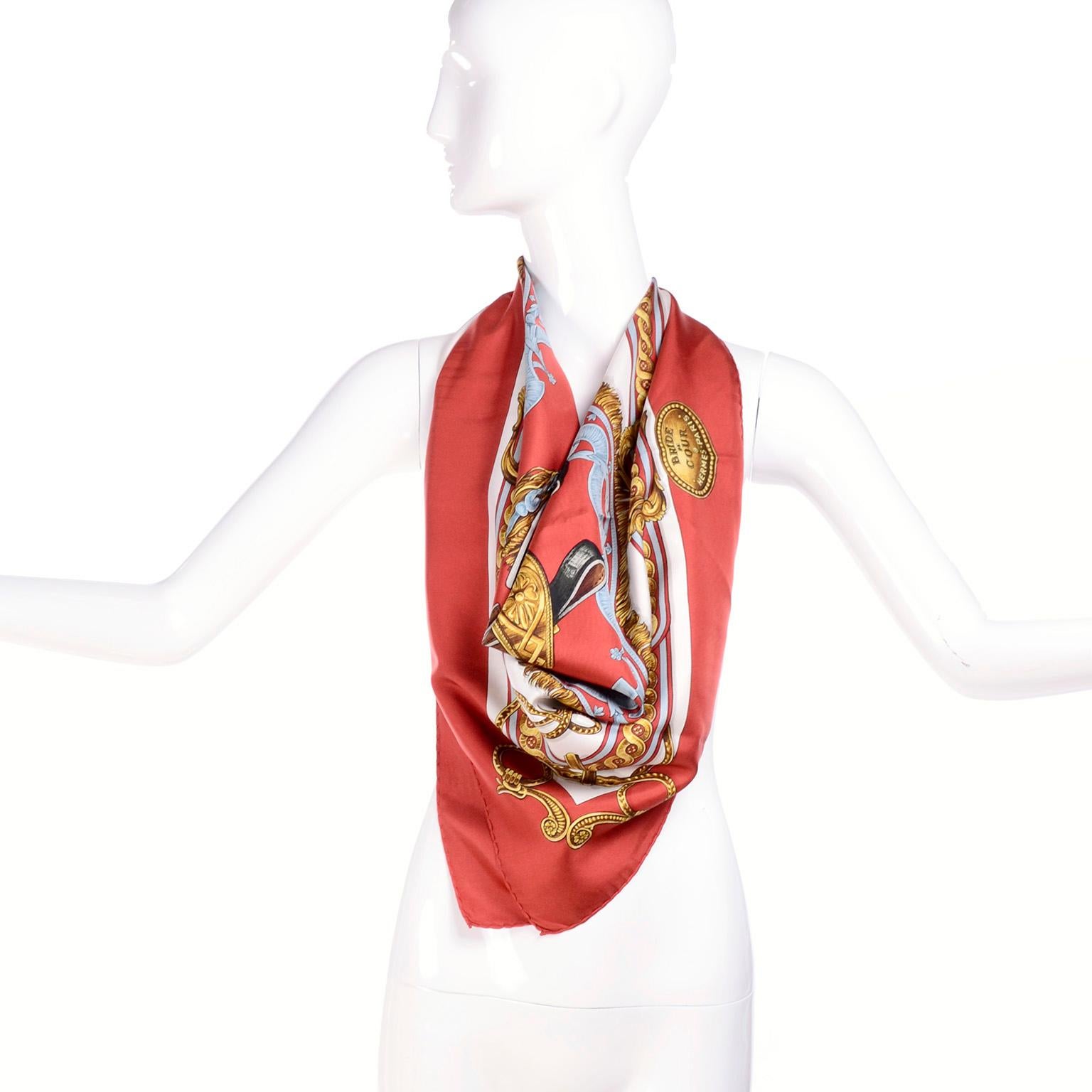 This beautiful vintage Hermes equestrian scarf was designed by Francoise de la Perriere in 1969. The scarf is in beautiful shades of rust red and blue with some yellow gold and it measures 35.