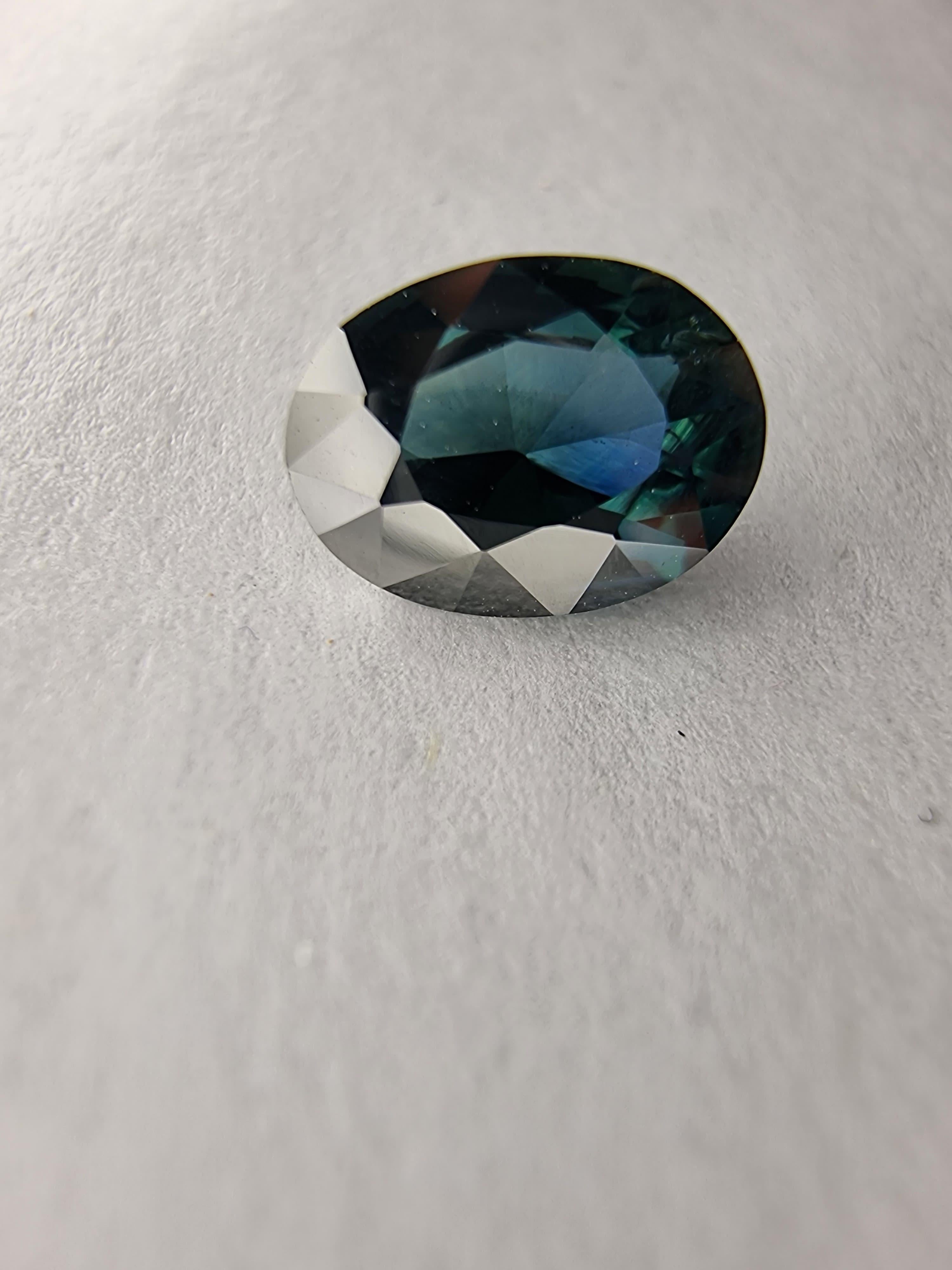  Lasciati conquistare dall'affascinante bellezza di questo zaffiro naturale blu acqua da 1,96 carati, sapientemente tagliato in una classica forma rotonda. Questa gemma presenta una miscela unica di sfumature blu e verdi, creando un ipnotico colore