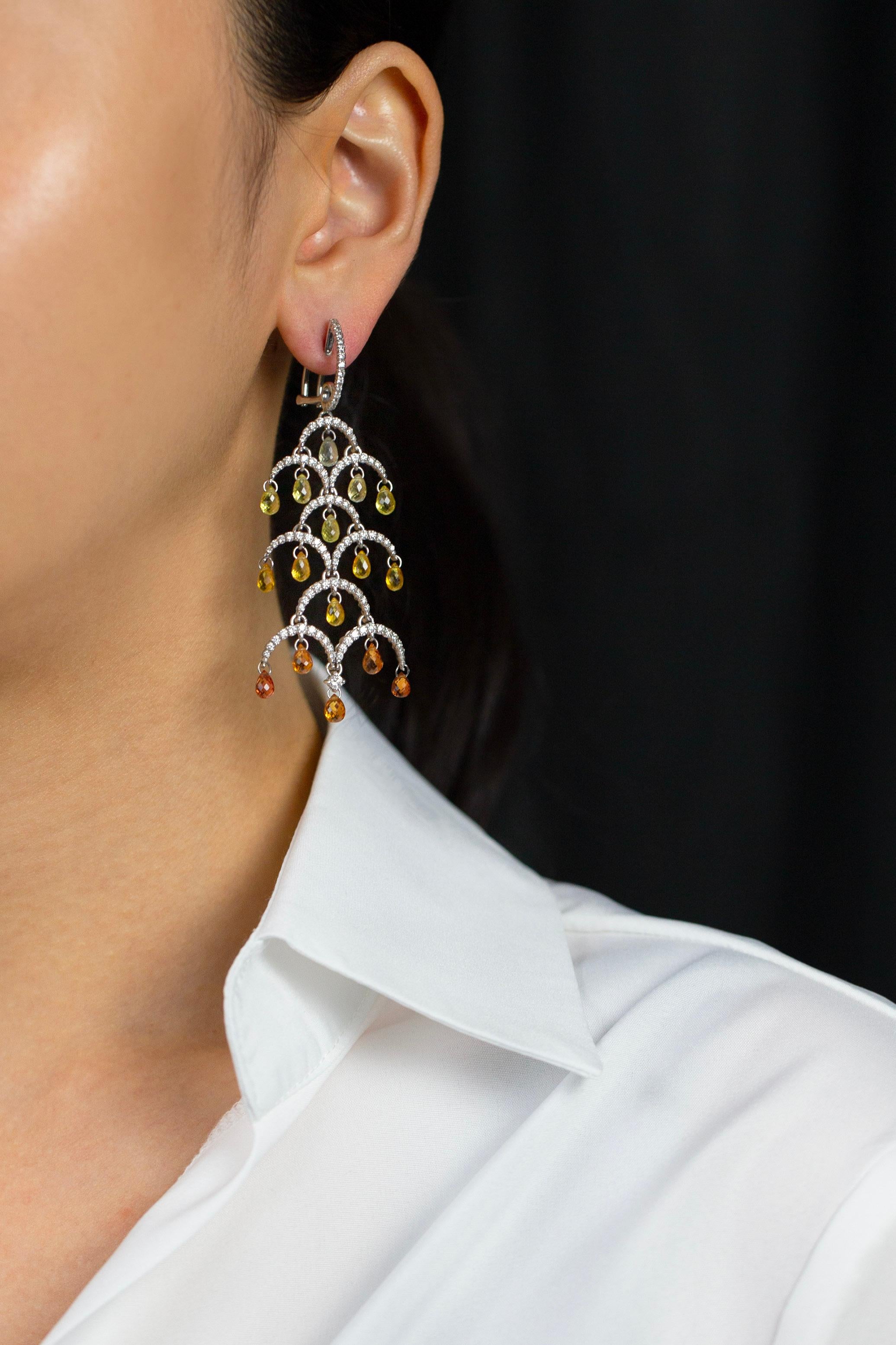 A delightful pair of chandelier earrings showcasing natural briolette orange sapphires graduating in color, suspended in a tree design accented with round diamonds. Diamonds weigh 1.97 carats total. Perfectly made in 18K White Gold. 

Style
