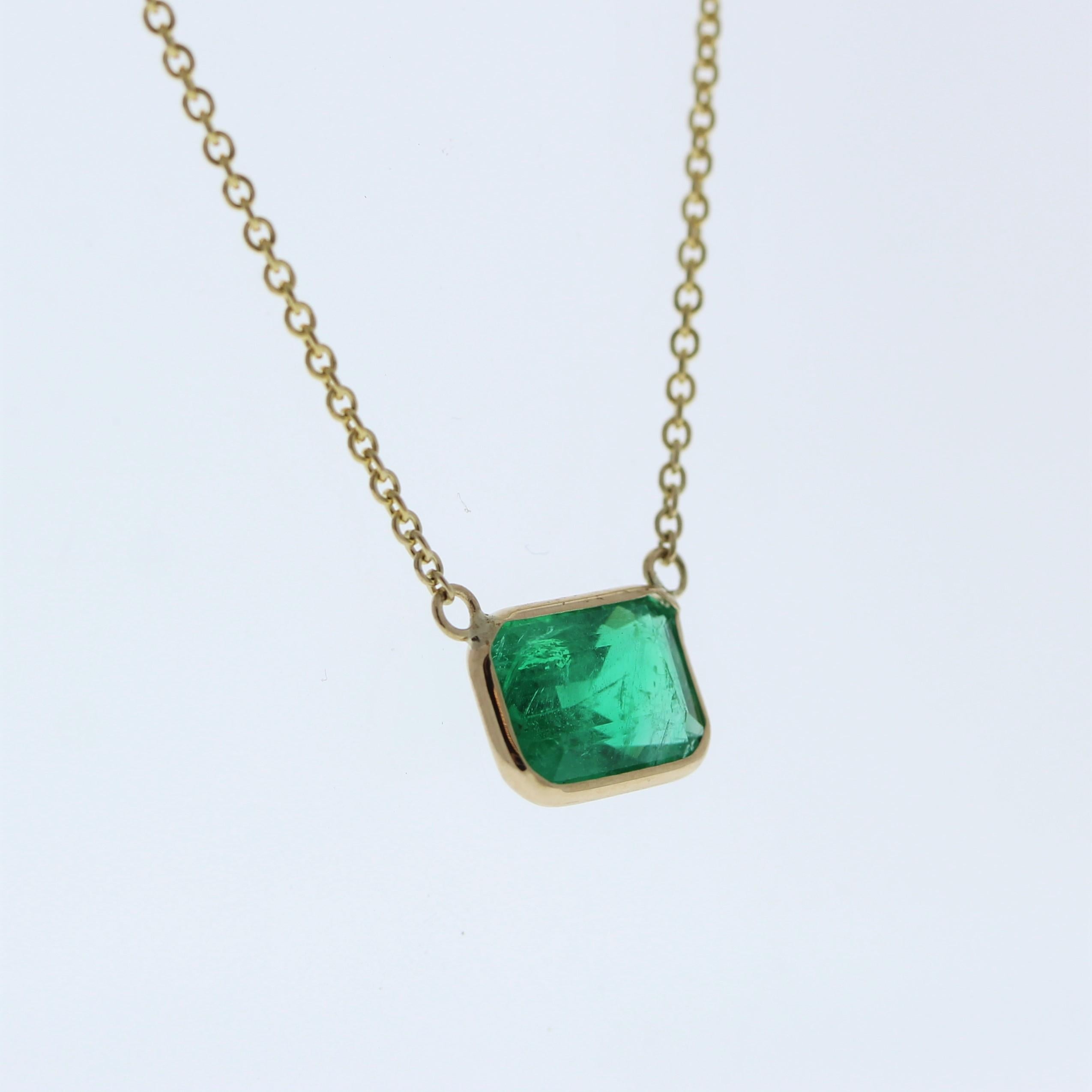 The necklace features a 1.97-carat emerald-cut emerald set in a 14 karat yellow gold pendant or setting. The emerald cut and the rich green color of the emerald against the yellow gold setting are likely to create an elegant and eye-catching fashion