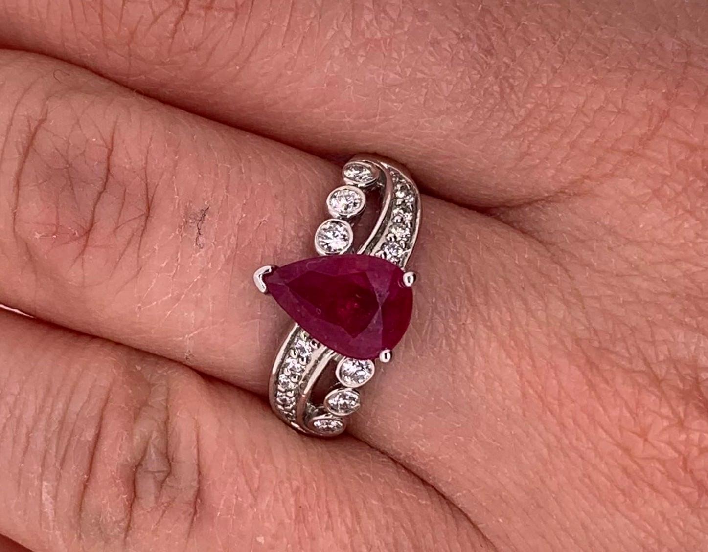 Material: 14k White Gold
Gemstone Details: 1 Pear Shaped Ruby at 1.97 Carats - Measuring 9.5 x 6.5 mm
Diamond Details: 16 Brilliant Round White Diamonds at 0.28 Carats. SI Clarity / H-I Color. 
Ring Size: 6.5. Alberto offers complimentary sizing on