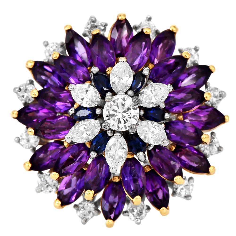 Amethyst, Diamond, and Sapphire Floral Cocktail Ring crafted 18K yellow and white gold.

The stunning 1970s ring features a central arrangement of diamonds, surrounded by layers of marquise-cut blue sapphires, purple amethysts, and additional