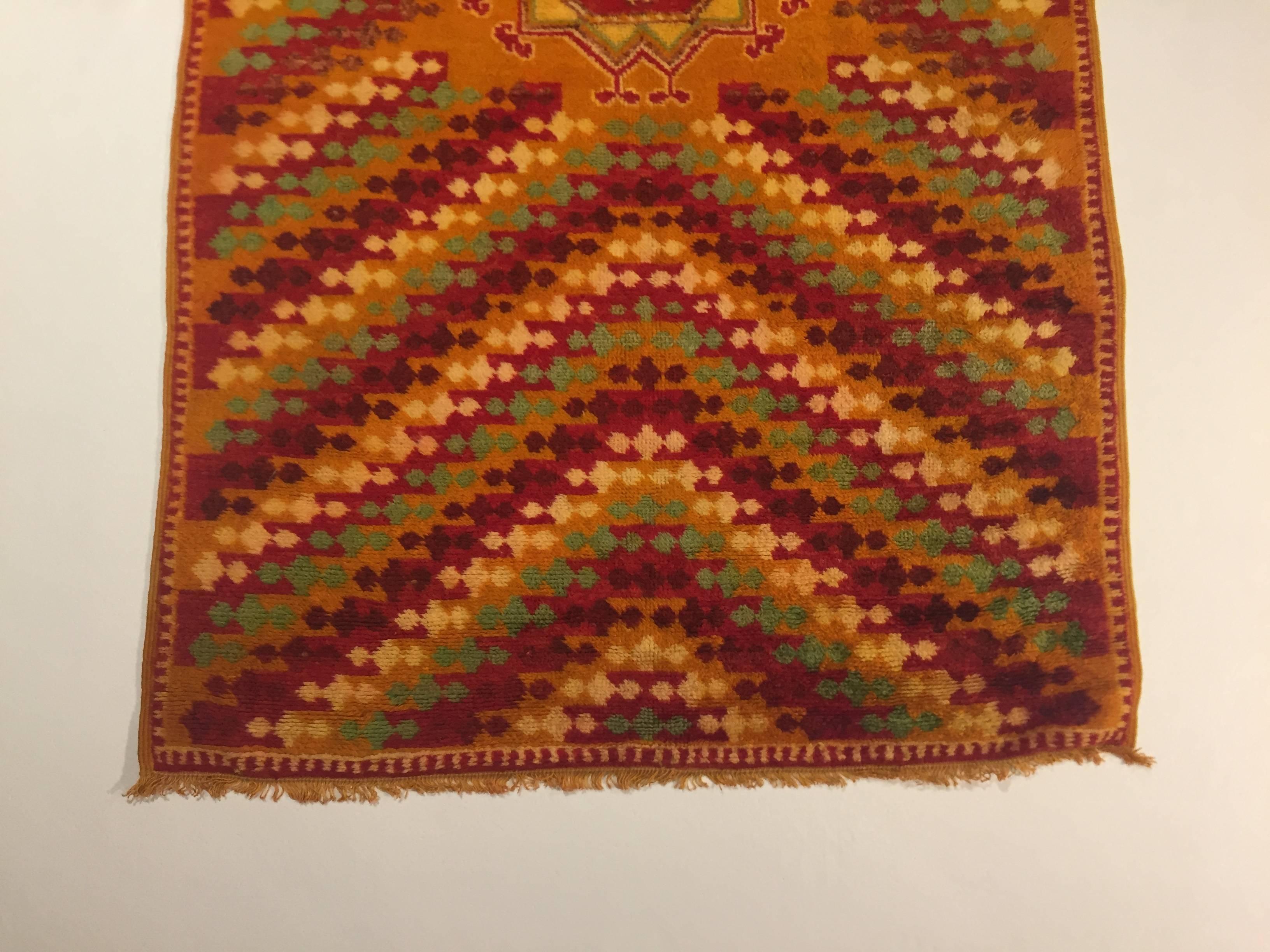 Berberteppich der Qualität Oouauzouite. Diese Art von Teppich zeichnet sich durch eine safrangelbe Wollstruktur aus. Es sind Teppiche, die der Phantasie von Frauen entspringen, die neben den klassischen Themen der Kultur der Nomadenvölker gerne