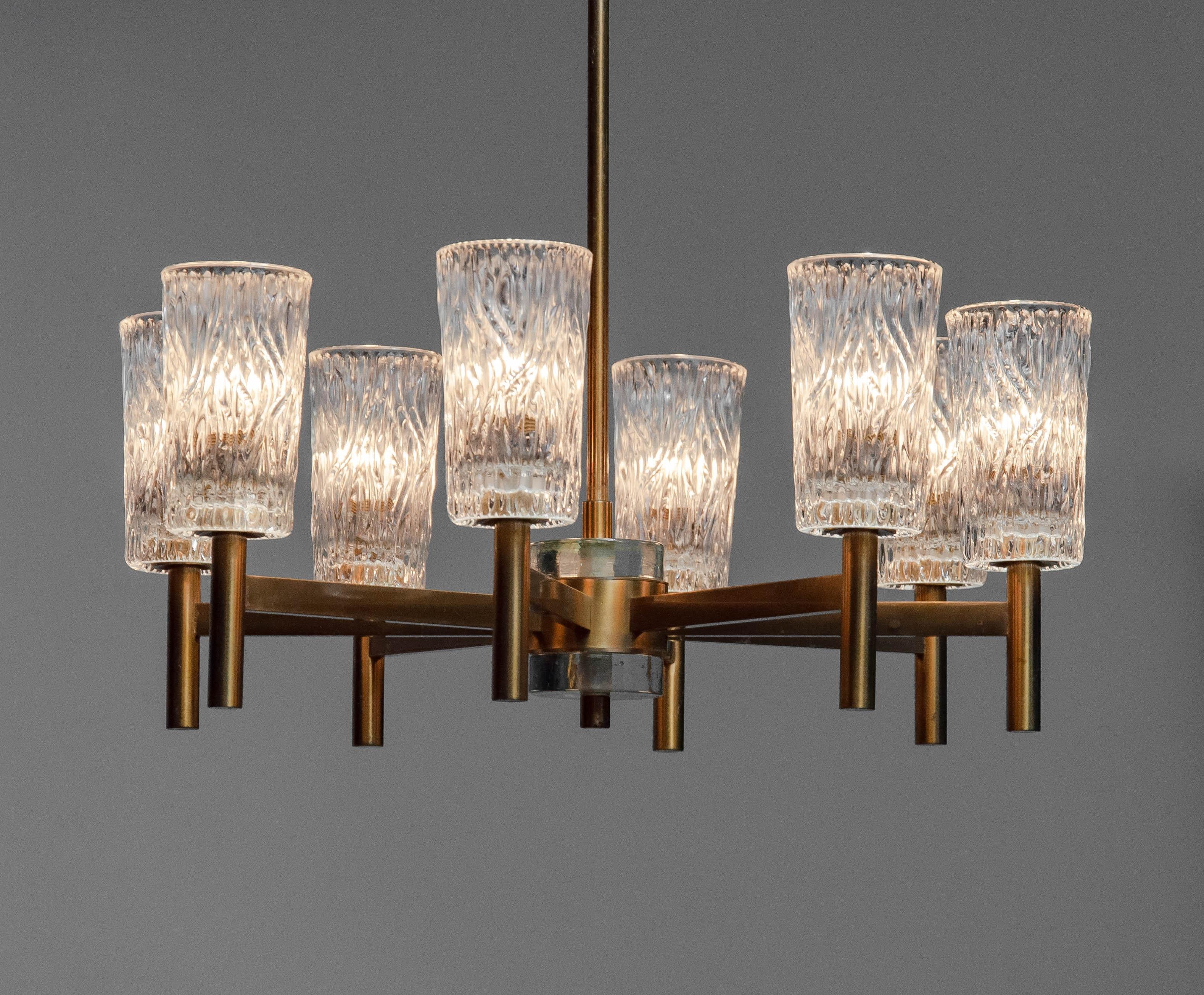 Beautiful eight arm chandelier in brass designed by Hans-Agne Jakobsson for Markaryd AB in Sweden in the 1970s. The eight brass arms supports art glass vases each 15cm / 5,91 Inches heigh.
Technically the chandelier is 100% and each arm has a E14