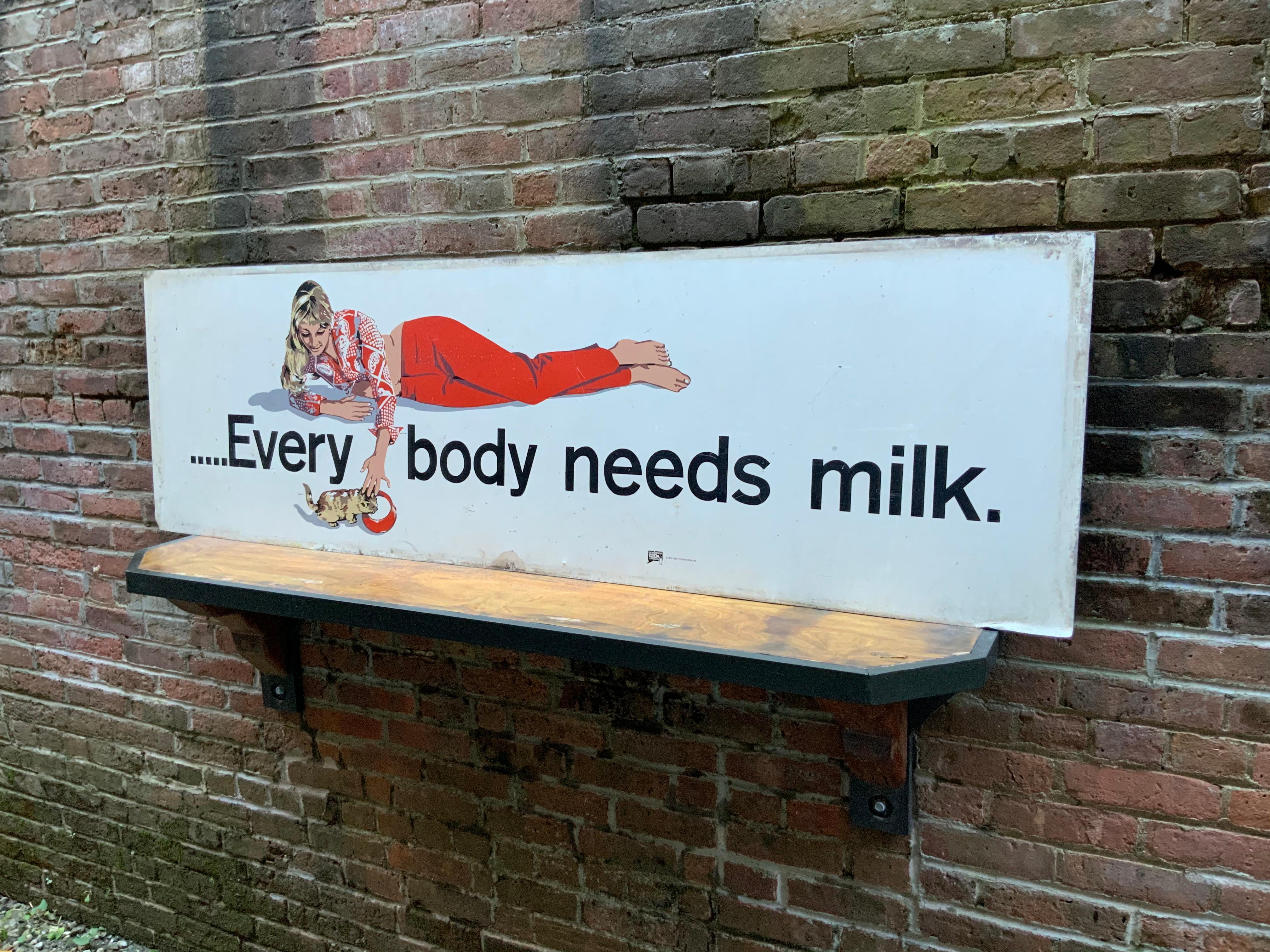 Amazing graphics on this sign promoted by the Connecticut Milk Foundation. The slogan reads, every body needs milk, circa 1970. Silkscreen graphics of a reclining lady feeding a kitten a saucer of milk. Good condition with minor wear. No visible