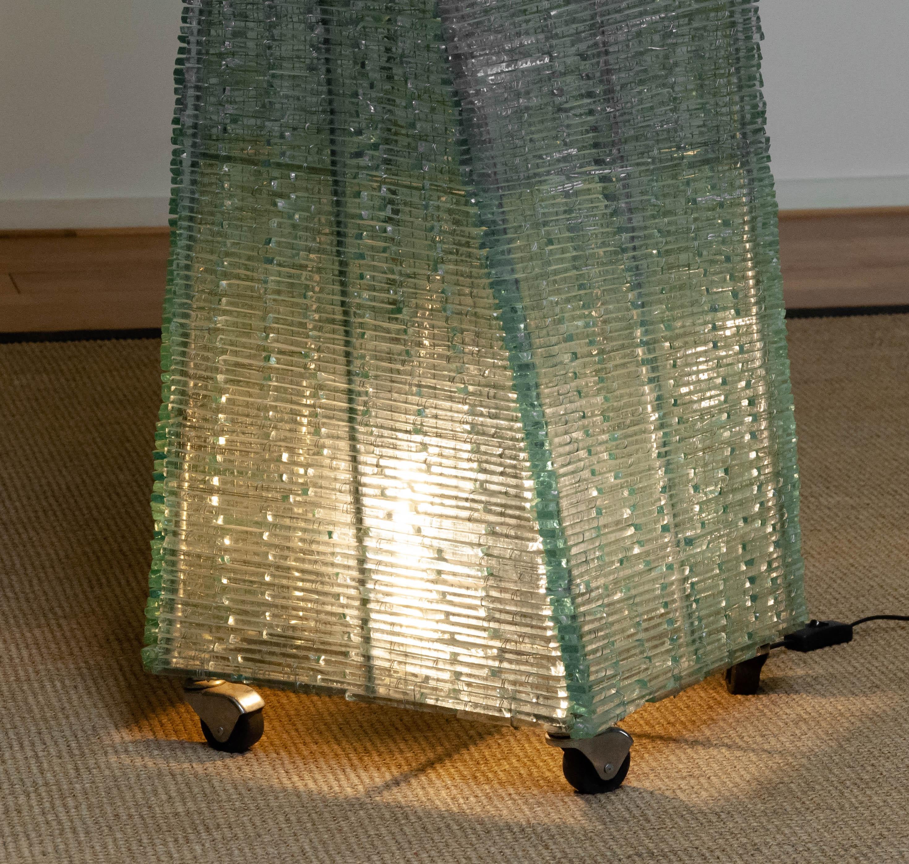 Extra große und majestätische handgefertigte ( 200cm / 79 Inches groß ) brutalistische Stehlampe aus tausenden einzelnen Glasstreifen, die mit Metalldraht an einem Metallrahmen ähnlich Pia Manu handgebunden sind.
Der Sockel ist 39cm / 15,4 Inches