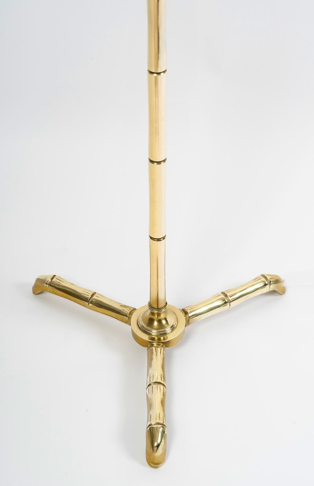 Composed of a large gilded brass stem resting on a base formed by 3 splayed feet distributed around the central stem, all in gilded brass imitating bamboo stems.
It is dressed with a cylindrical shade in off-white cotton reworked to match.

1 bulb