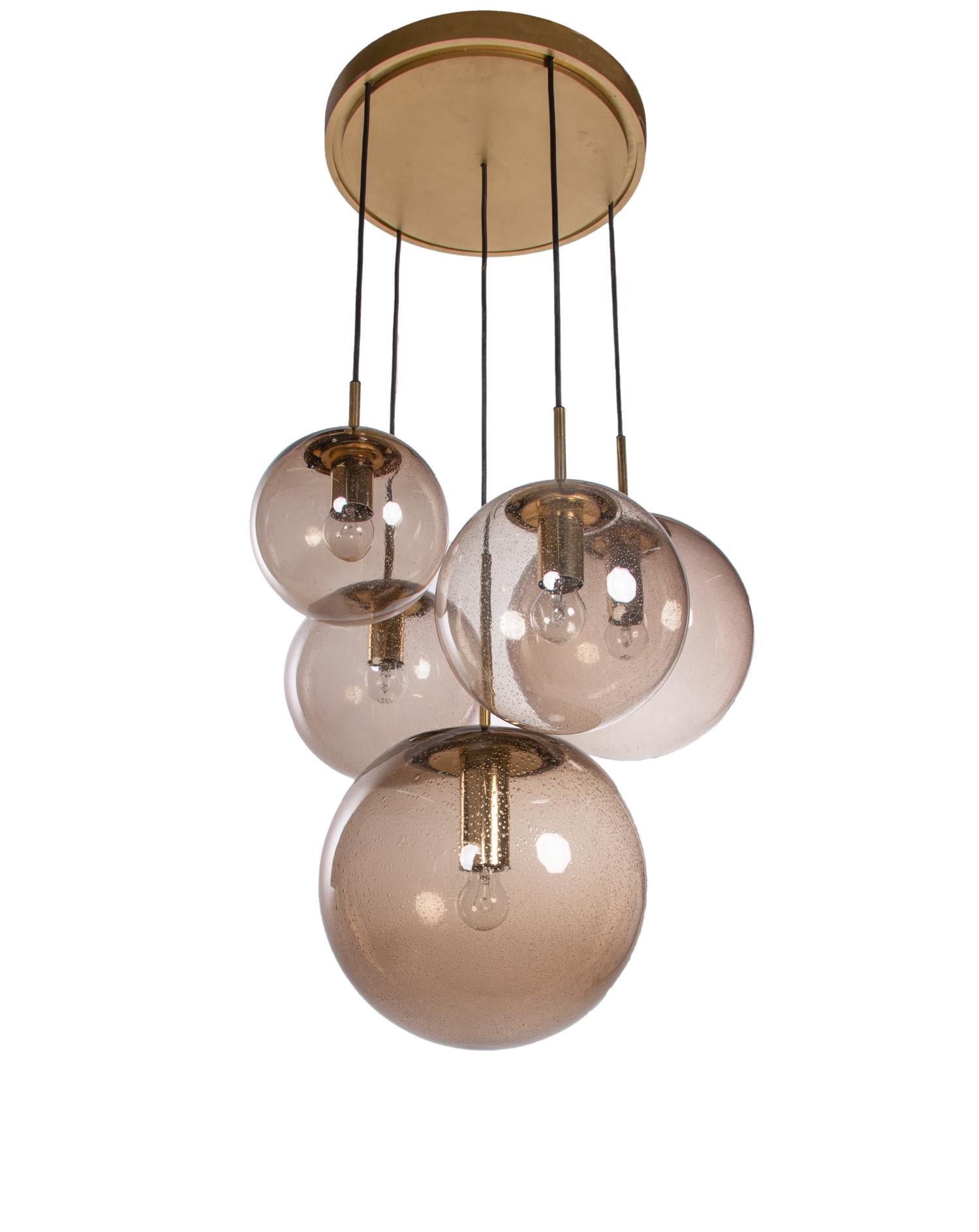 Large cascading chandelier with five different sizes of smoked handblown glass globes on a brass frame. 
Chandelier illuminates beautifully and offers a lot of light. With this light you make a clear statement in your interior design. A real