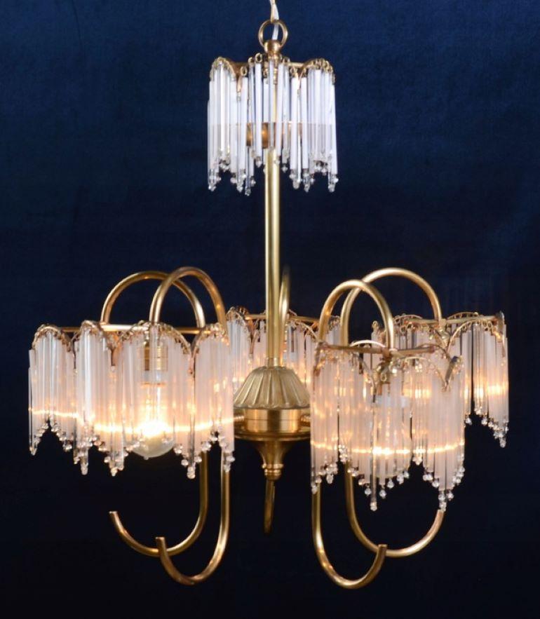 Chandelier made of  brass. The lamp is very original thanks to the arms. They are made of half-rings, which instead of lampshades end with 5-arm constructions from which crystals hang. The same motif appears in the center. The crystals are