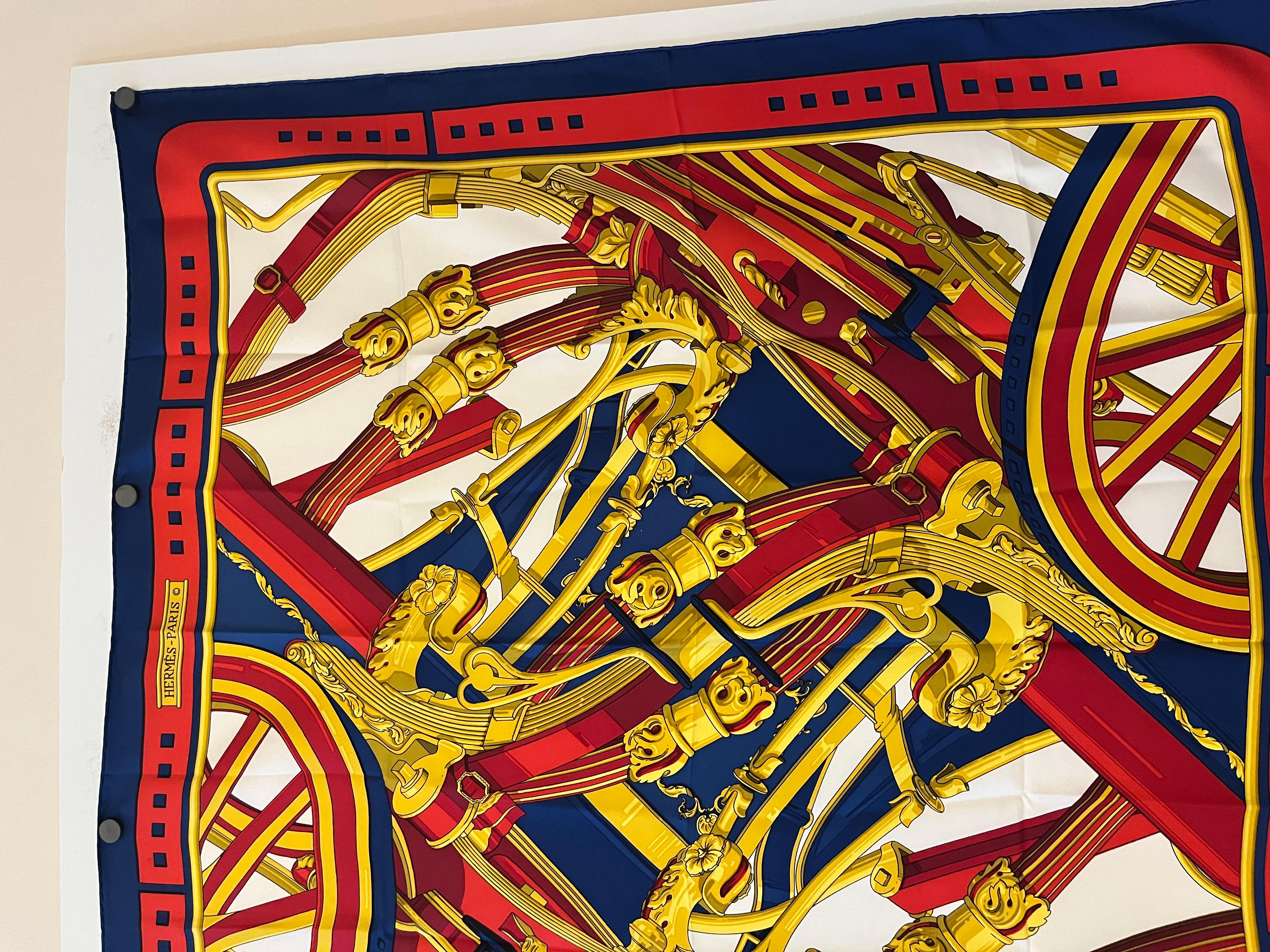 This is a 1970 Hermes silk scarf designed by Cathy Latham. The design represents movement featuring carriage wheels, pistons and highly decorated gold-tone fittings. In fact it also represent the House of Hermes beginnings.
The silk scarf is 35