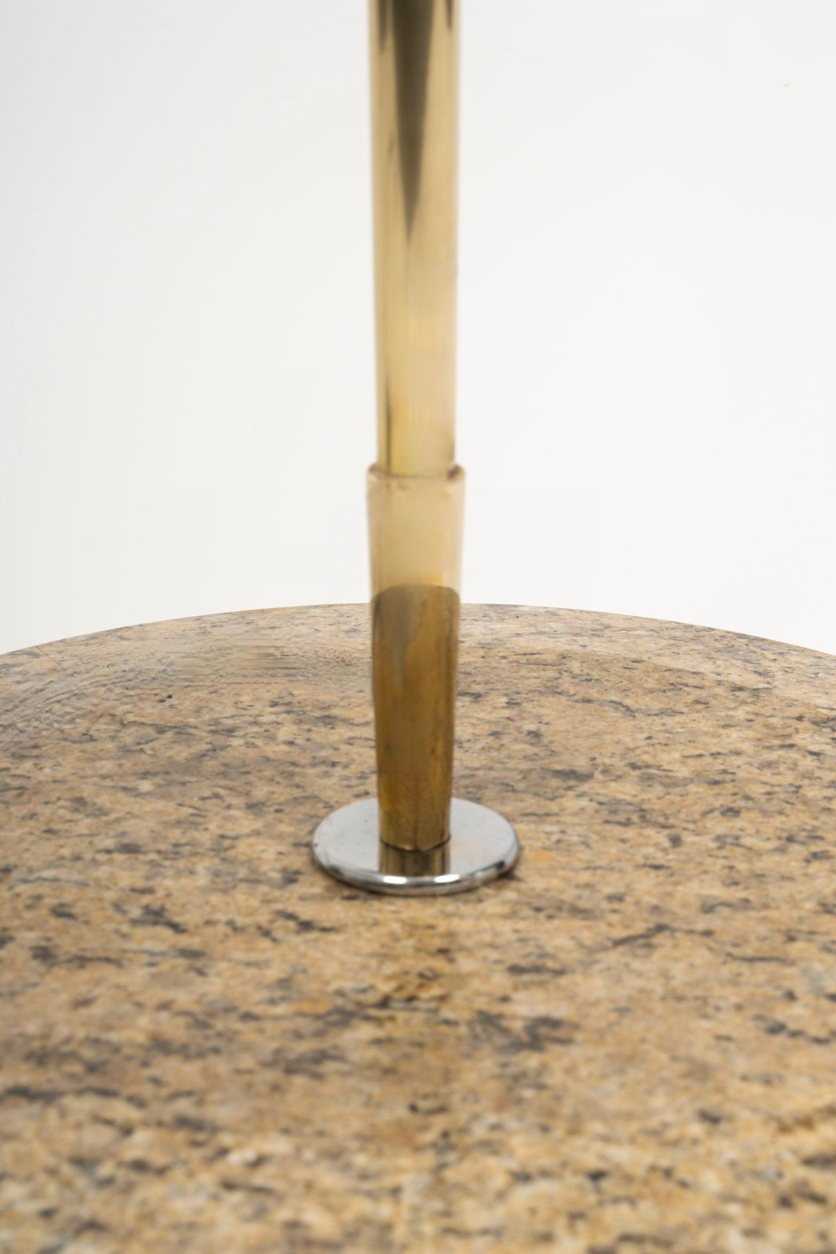 Compuesta por una gran base redonda de granito de Bretaña pulido que soporta un largo vástago que sirve de brazo de iluminación cónico de latón dorado, rematado por una pantalla trapezoidal de algodón blanco roto (reproducción idéntica).

1 bombilla.