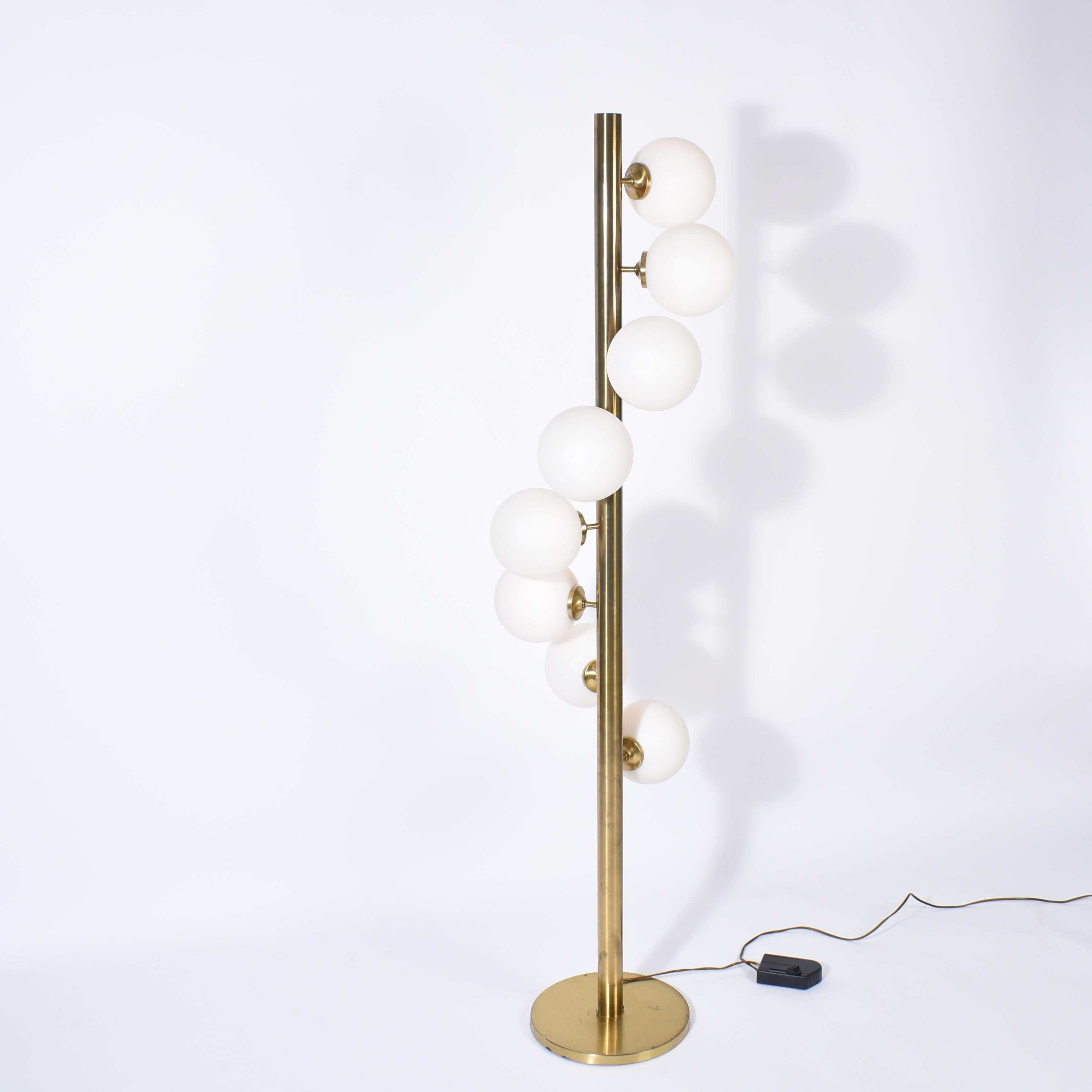 Big brass mid-century modern floor lamp.
It was designed and manufactured by Megal AG, in Switzerland, during the seventies.
Around the cylindric brass pole are disposed in spiral eight opaline spheres.
The design is very clean and elegant, with