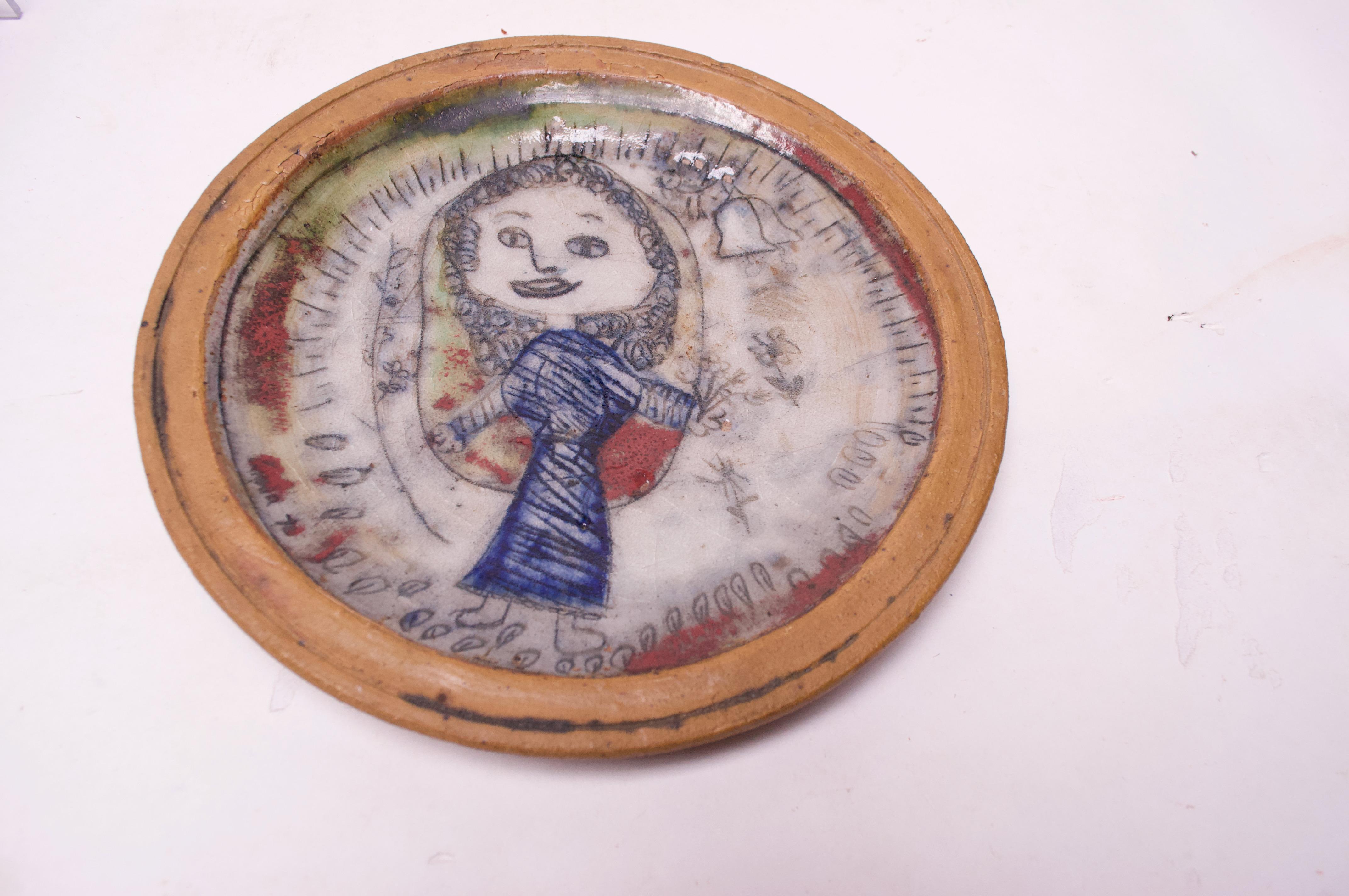 Charming outsider art charger / decorative plate depicting a jovial young girl. Pleasant color palette and figure with age-appropriate crazing to the glaze. Otherwise, in very nice, vintage condition. 
Dated 4/15/70 to the reverse. 
  