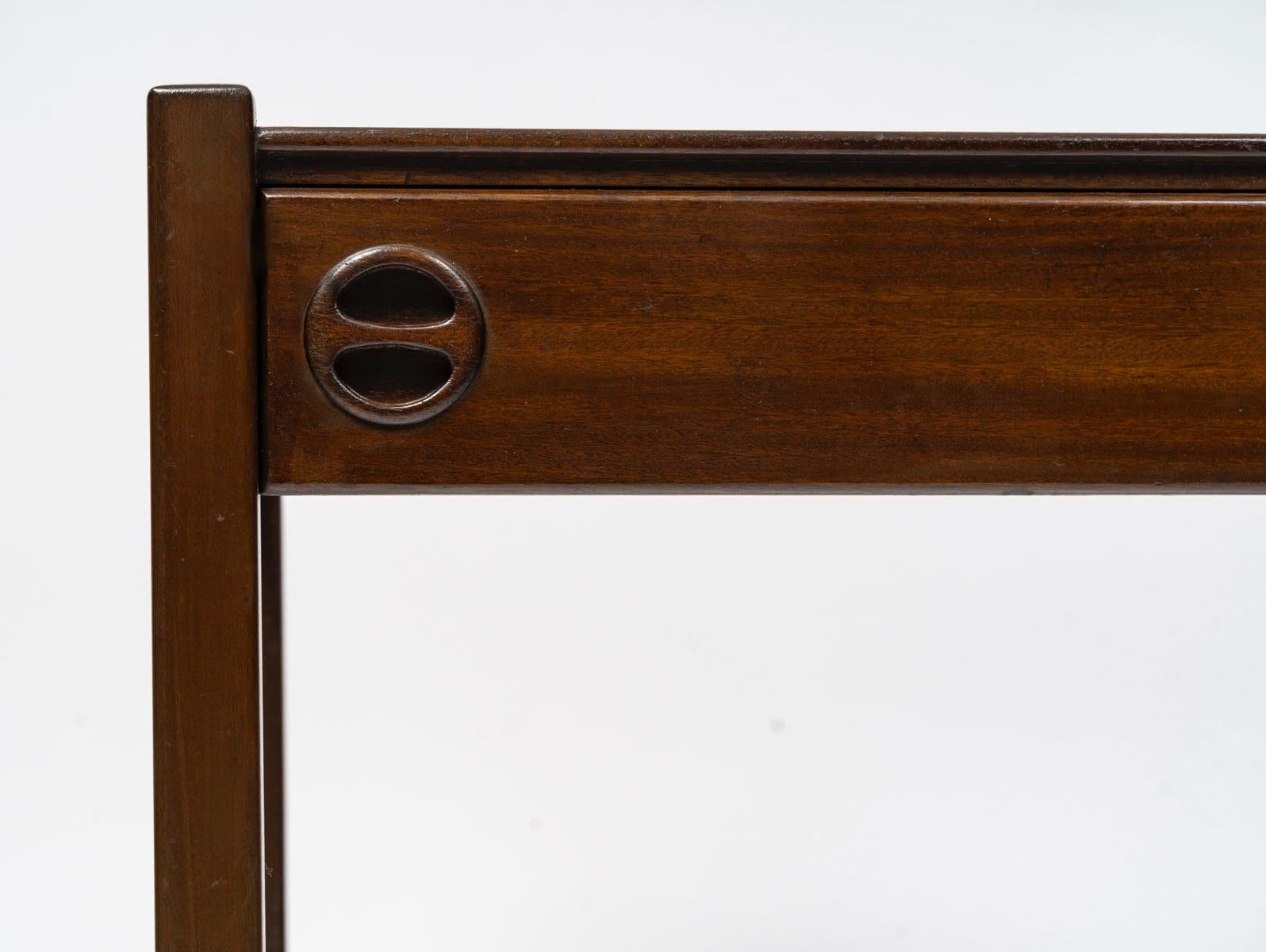 Composed of a rectangular box with space at the top for lamps or various objects, it is equipped with a drawer just below, featuring two elegant handles.
It rests on four square legs reinforced by an H-shaped crossbar at the bottom.
The entire piece