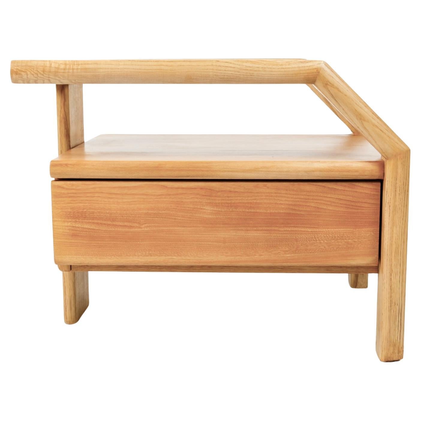 Composed of a suspended wooden box opening onto a drawer at the front of the bedside table.
Rectangular wooden dishes, rounded at the corners, run along the bedside table top, down at an angle, then rest on two lateral legs on the side of the
