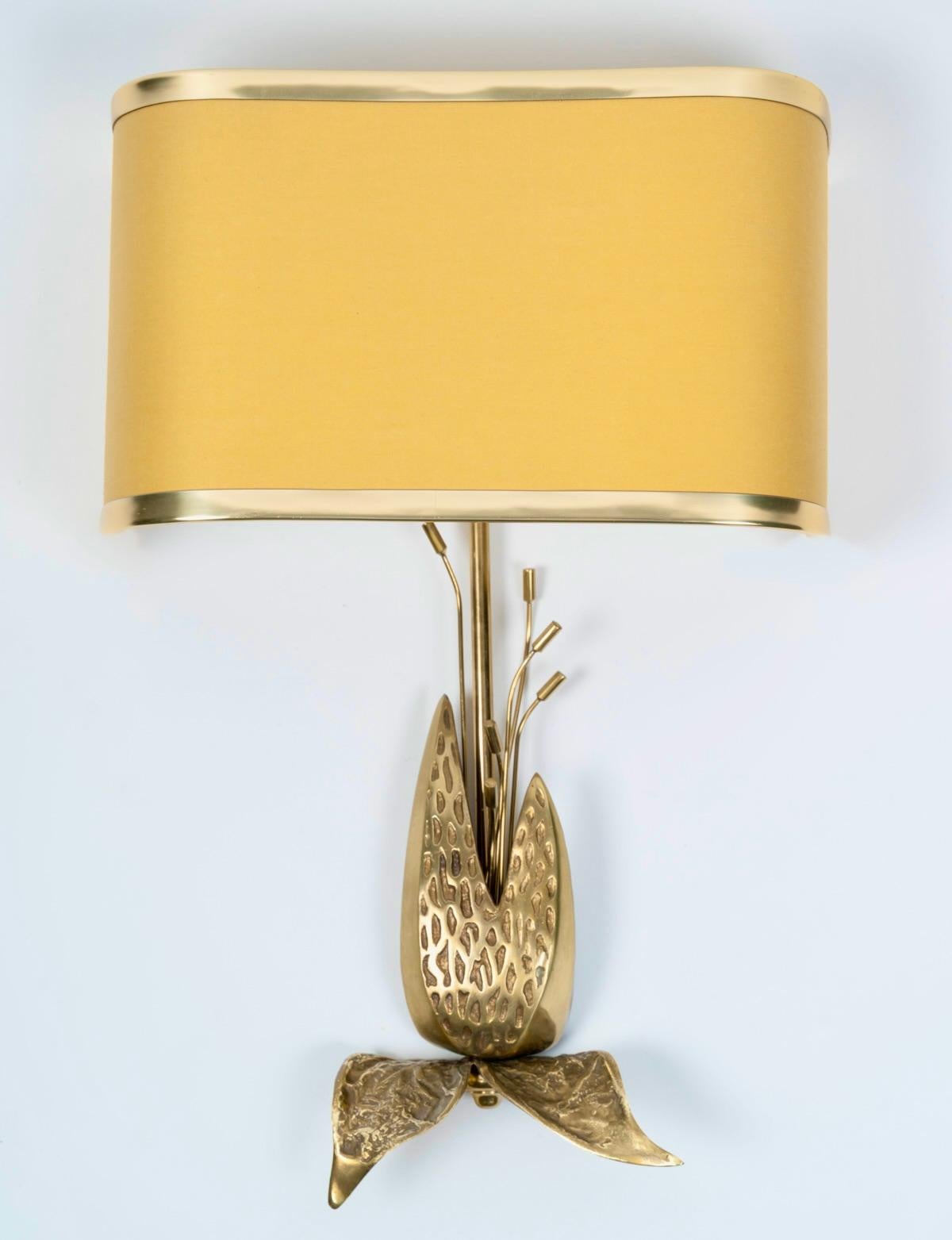 Pair of sconces by Maison Charles en bronze et laiton doré.

Comprising a round central rod in gilded brass, highlighted at the bottom by a decoration composed of flowers, foliage, and pistils in gilded bronze, topped by a bronze-colored lampshade