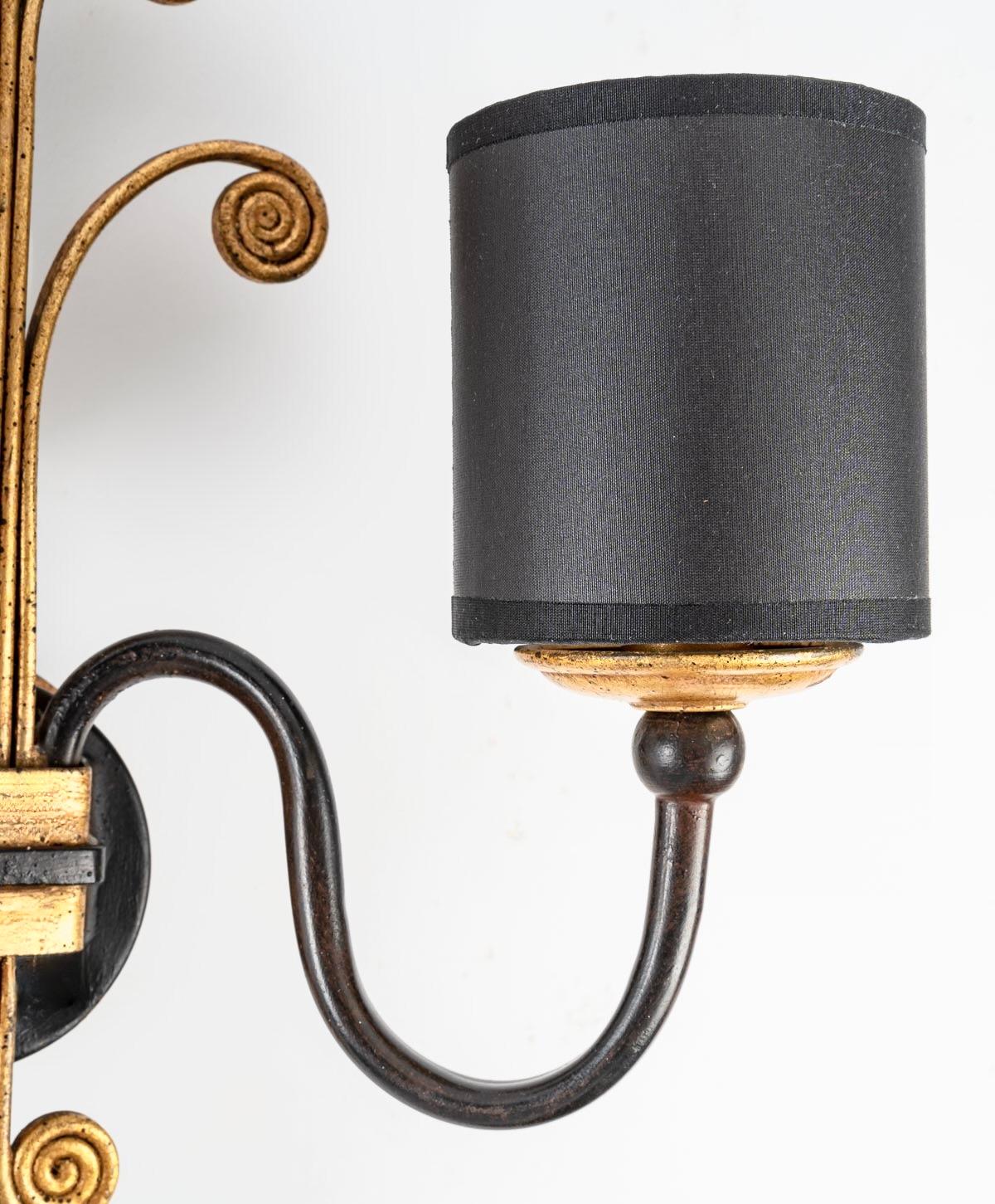 Composed of a round wall support on which is placed in the lower part two black wrought iron light arms placed on either side of the wall lamp, they are dressed with two cylindrical black cotton lampshades redone identically and underlined at the