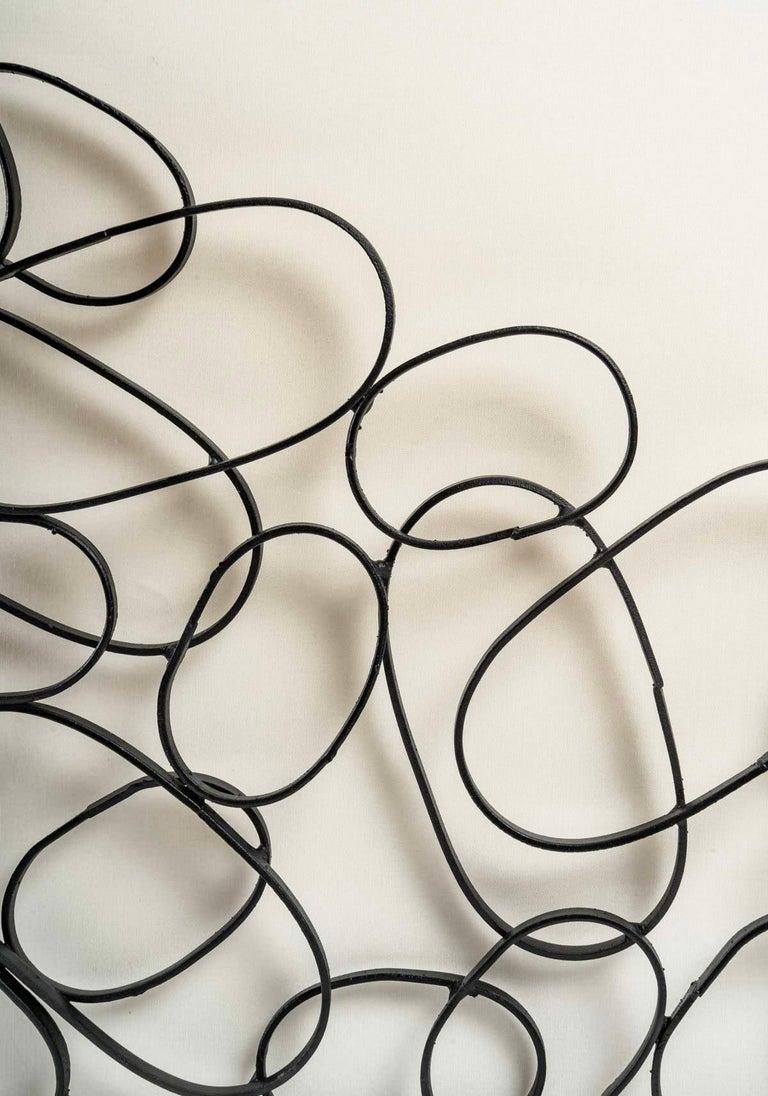 Compuesto por una estructura de hierro forjado negro de forma rectangular decorada con multitud de lazos ovalados de diferentes tamaños ensamblados por pequeños puntos de soldadura formando una jaula, obra artesanal.
En el interior, una gran