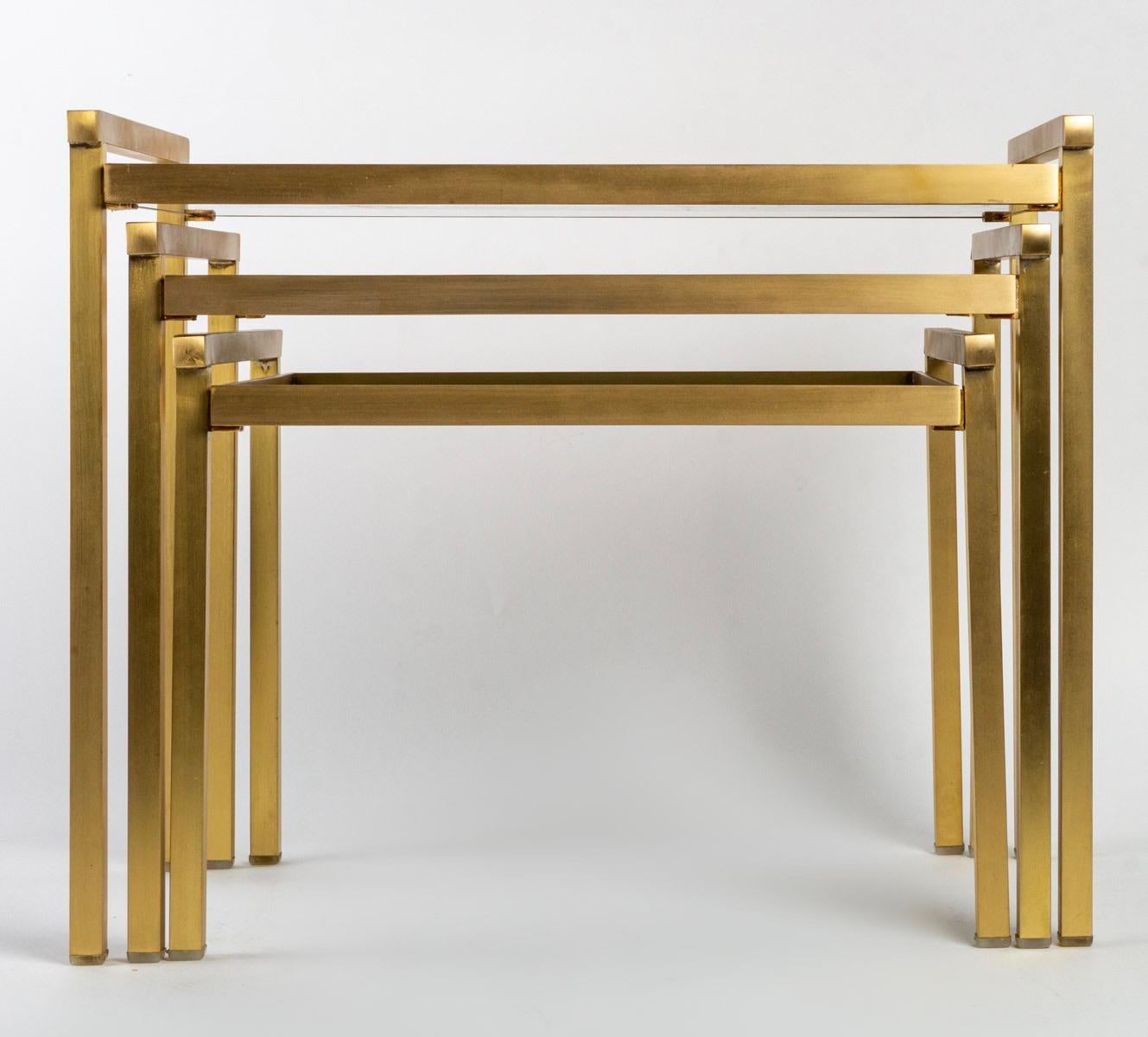 The nesting tables are composed of a set of small light tables that fit into each other in order to save space. 
The structure of the tables is in golden brass and the tops are in glass.