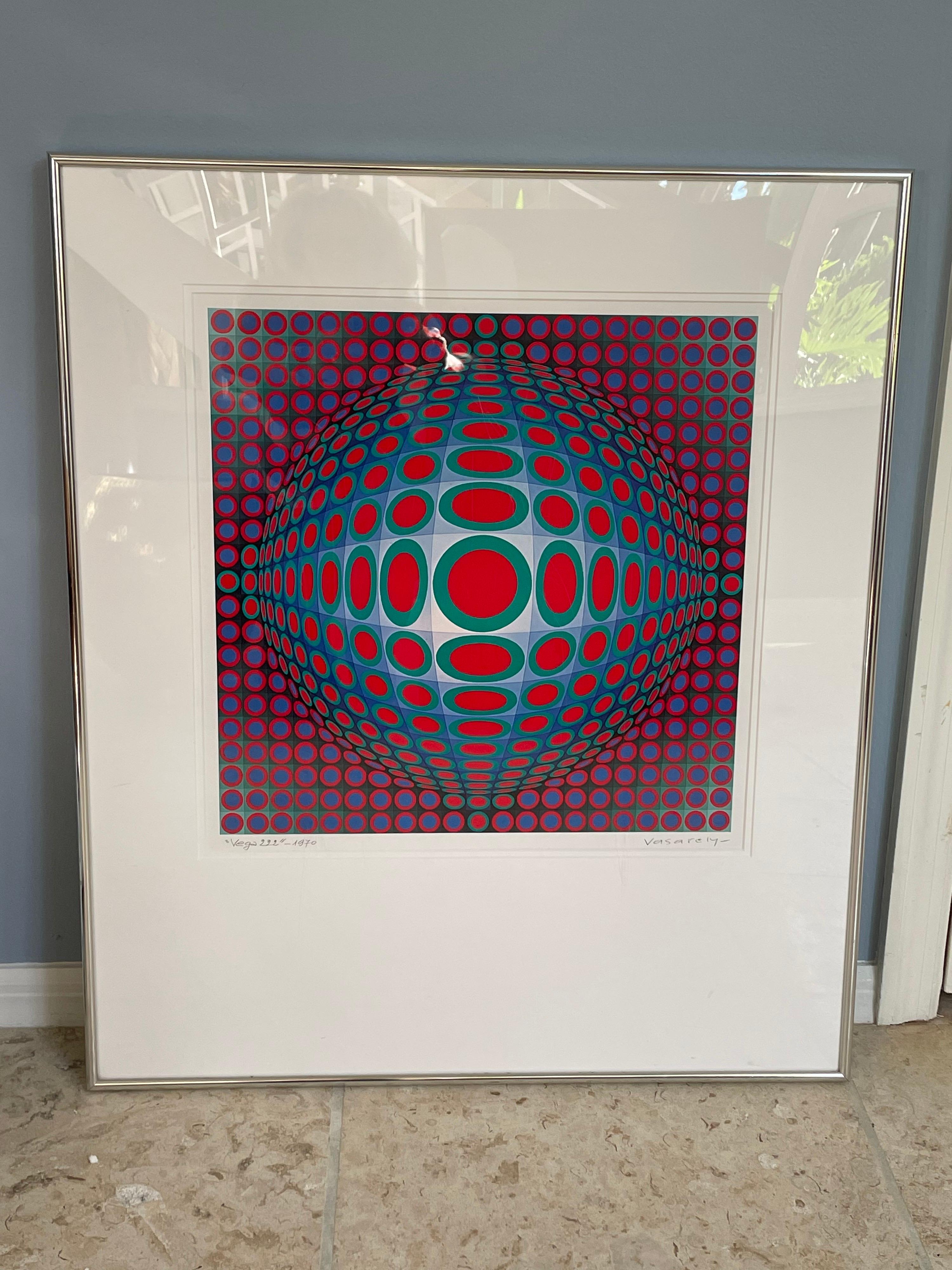 This is a vintage 1970 serigraph by Vasarely titled “Vega 222 “ in a silver metal frame and plexiglass.