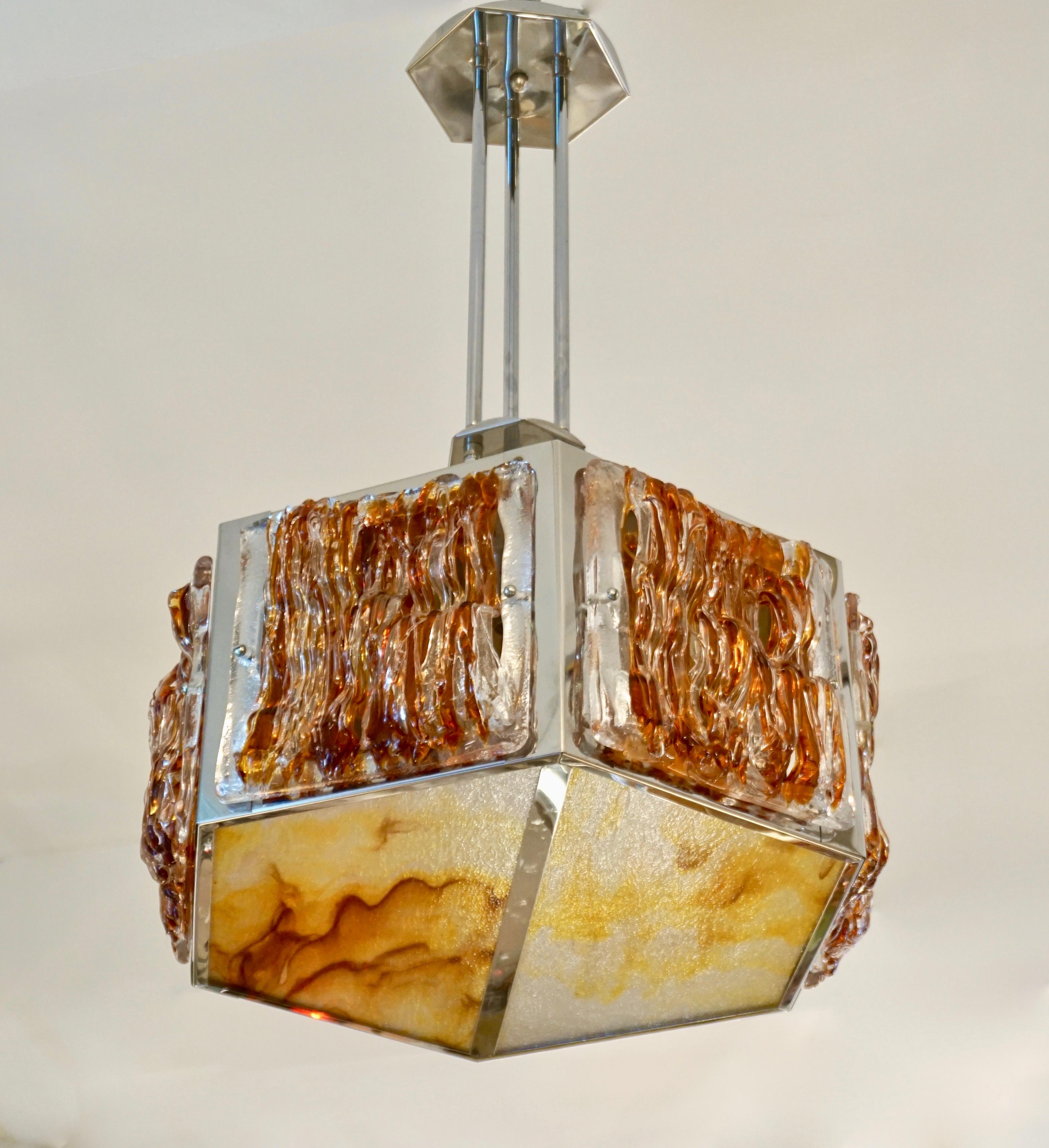 A rare Italian Design Mid-Century Modern chandelier by Mazzega, the nickel structure has a geometric hexagonal shape, repeated in the canopies, with 6 airy organic side panels in crystal clear and orange Murano glass worked in filament fretwork, a