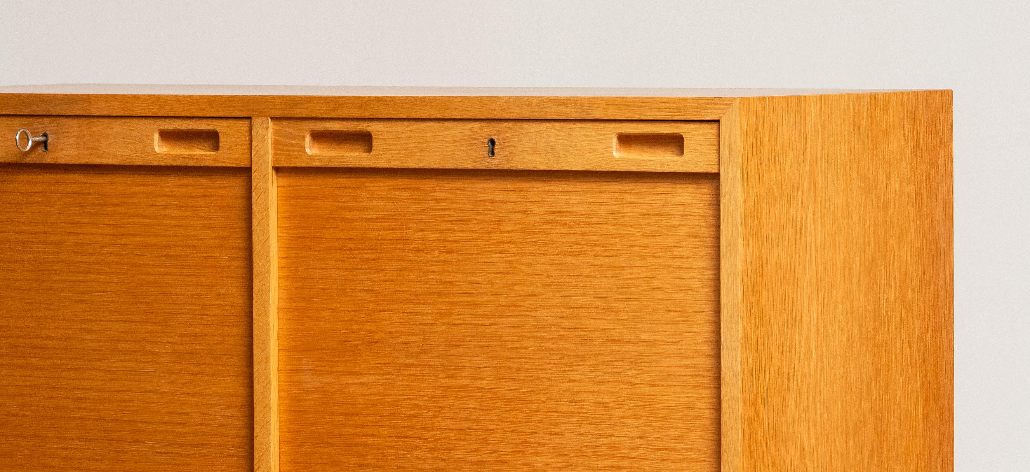 A Scandinavian drawer / filling cabinet in white oak having two slatted tambour doors that conceals two adjustable shelves on one side and eleven drawers to the other side. All drawers can be taken out.
The overall condition is good.