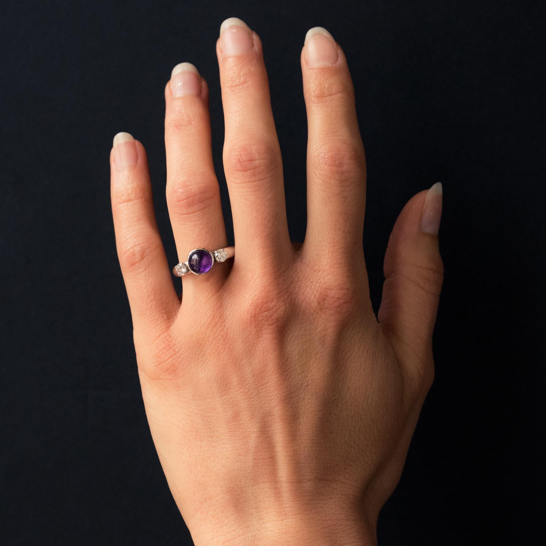 Ring in 18 karat white gold.
Timeless retro ring, it is composed of a white gold domed ring which supports an amethyst cabochon closed set bezel on either side by a modern brilliant-cut diamond set with claws.
Amethyst weight: about 1.30