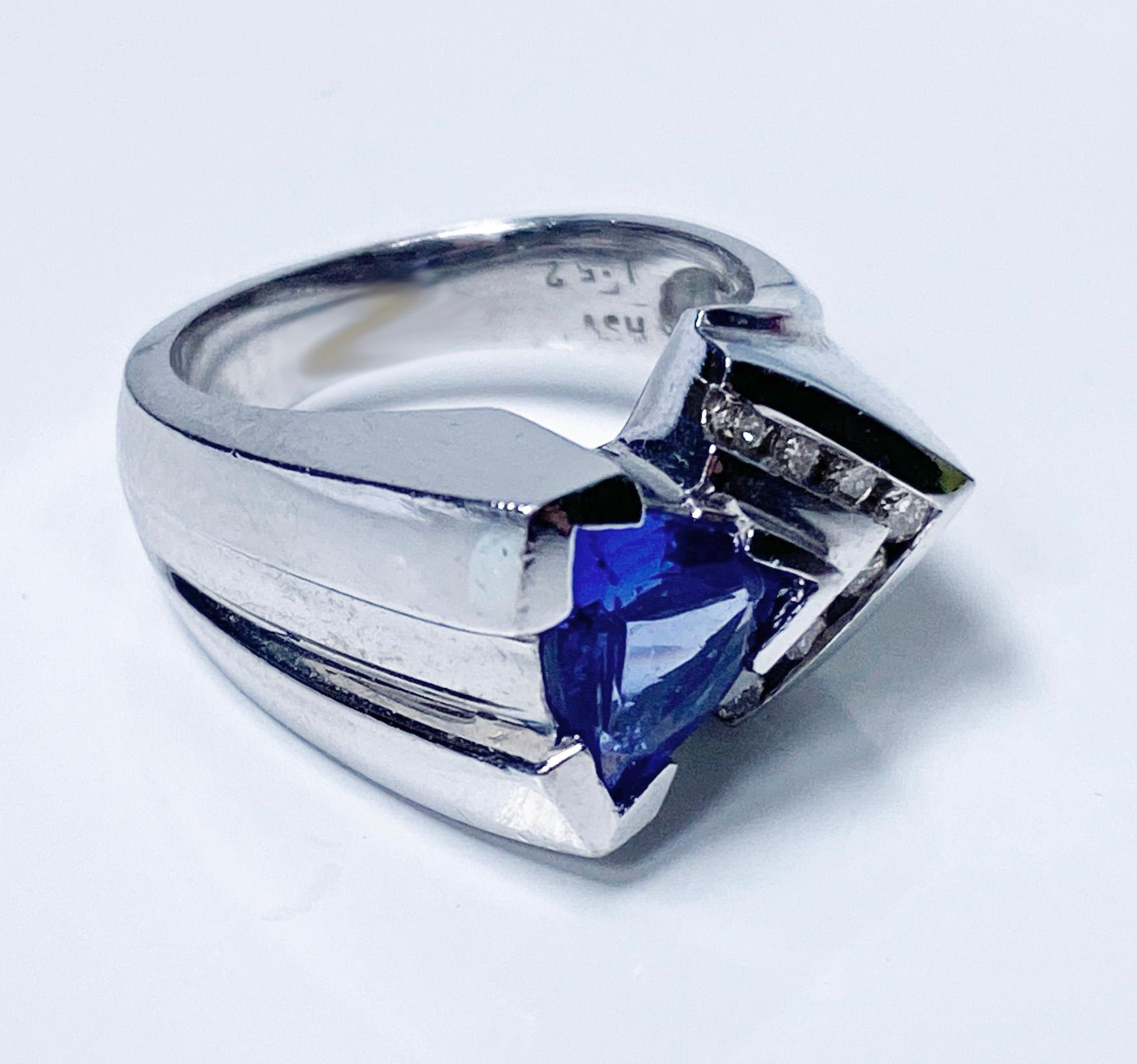 1970’s 14K White Gold Tanzanite Diamond Ring. The custom made Ring set with a trilliant intense Violet Blue very lightly included Tanzanite, approximately 1.55 cts, gauging 8.75 x 8.05 x 3.85 mm; and seven round brilliant cut Diamonds all in a