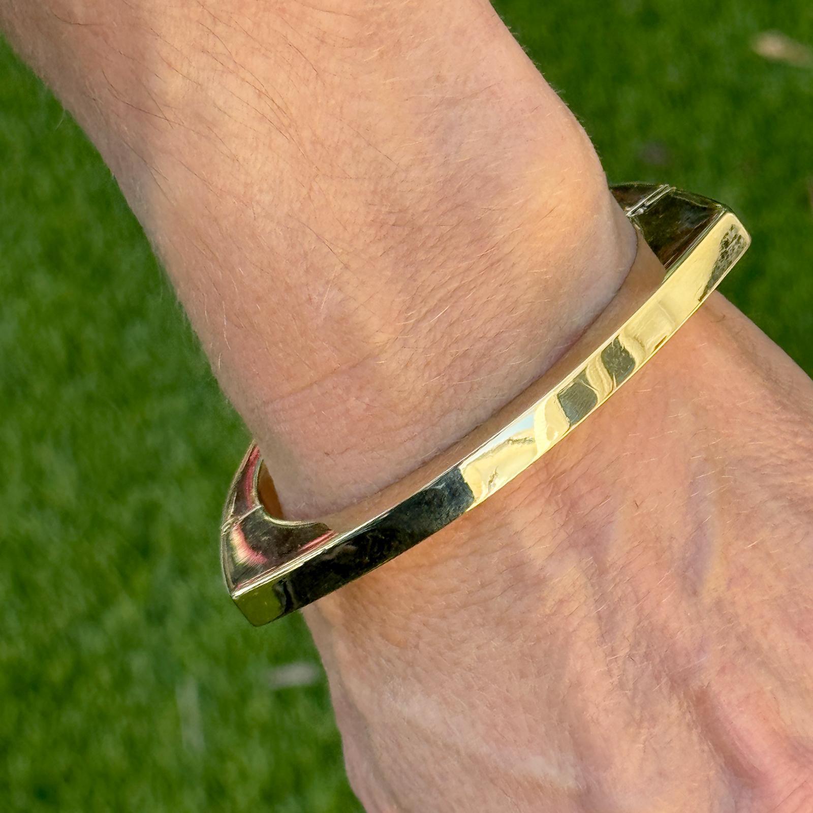 Contemporary asymmetrical hinged bangle crafted in lustrous 14 karat yellow gold. The 1970's vintage bangle features squared off edges and measures 6mm in width, 2.25 inches in diameter, and will fit up to a 6.0 inch wrist. Weight: 25.7 grams.