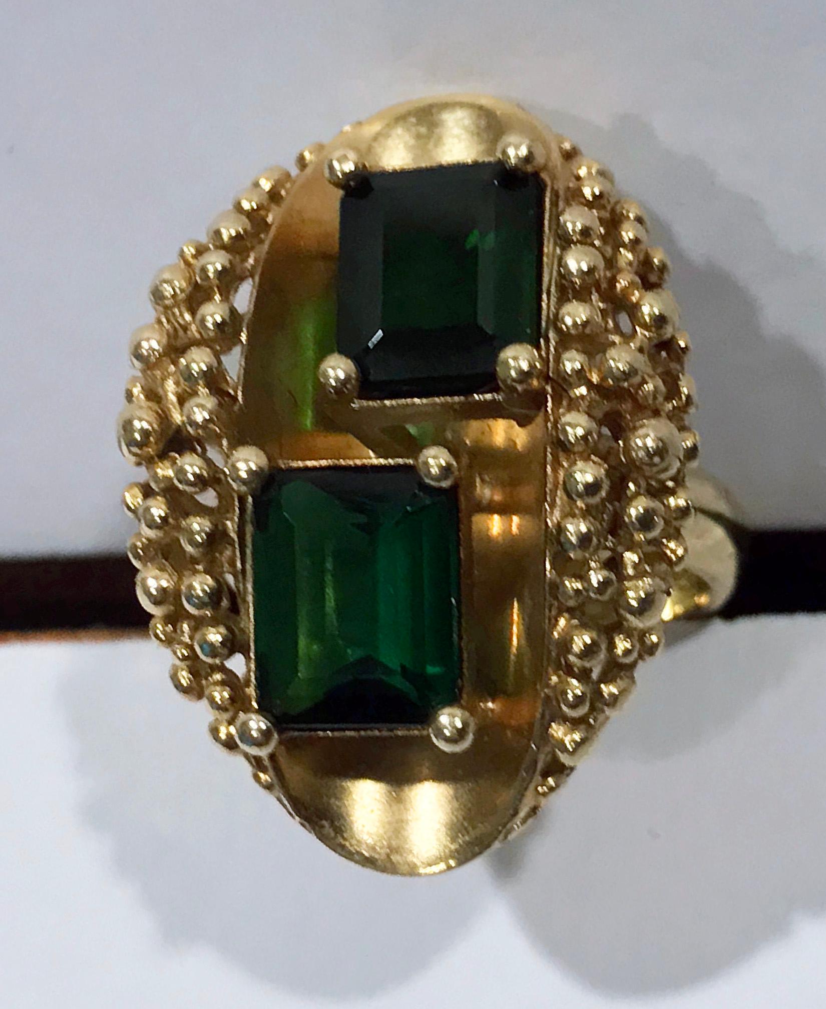 18K Abstract Tourmaline Ring 1970’s. The green gold ring depicting an open `oyster’ like top set with two emerald cut green tourmalines, gauging approximately 8.5 x 7.5 mm, 2.50 cts each the mount further accented with a granular `sand’ bead