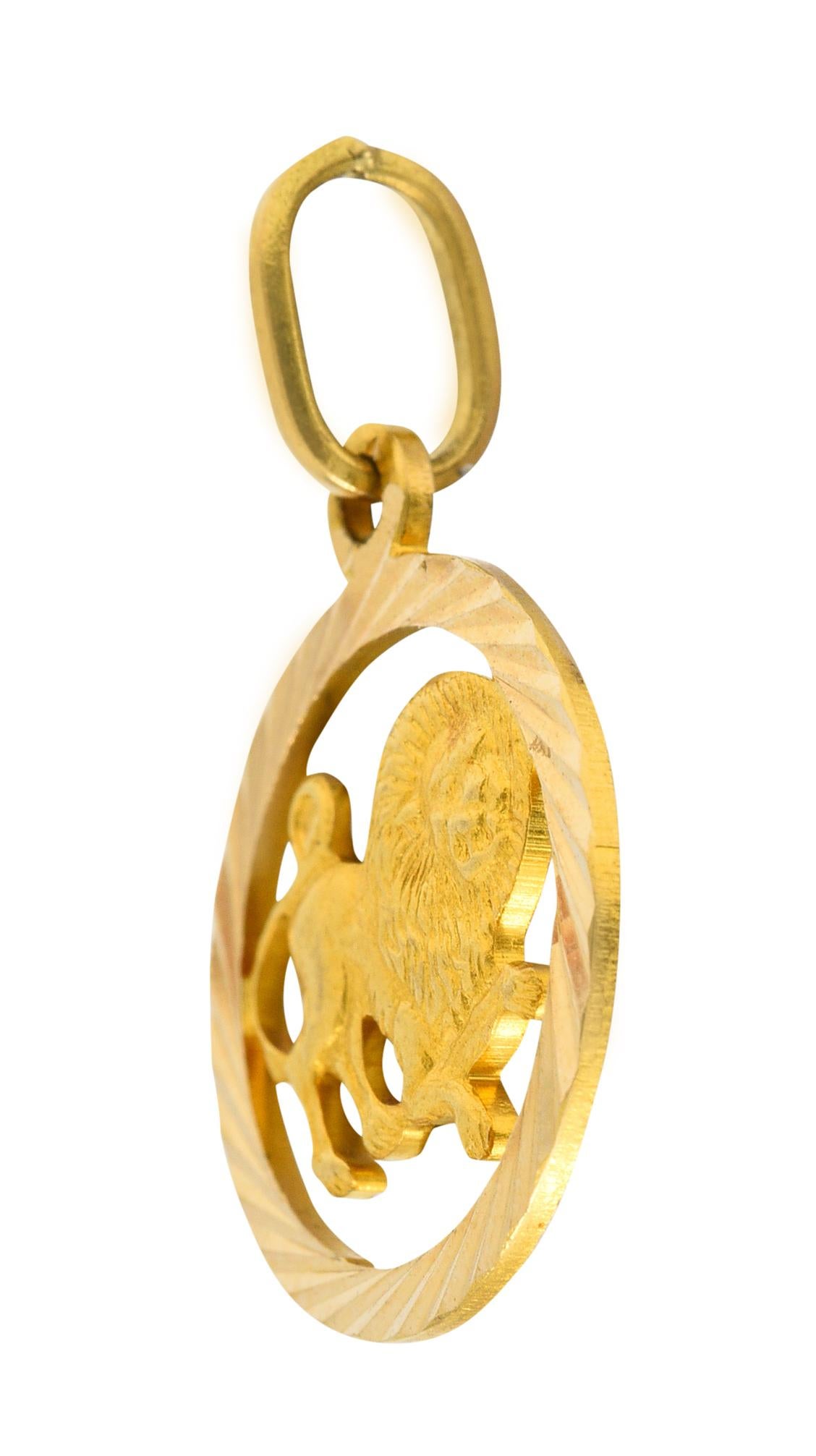 Designed as a pierced open circle with a deeply faceted surround

Centering a highly rendered image of a lion

With a wild mane and crouching posture

With Italian assay marks for 18 karat gold

Circa: 1970s

Measures: 11/16 x 1 inch (including jump