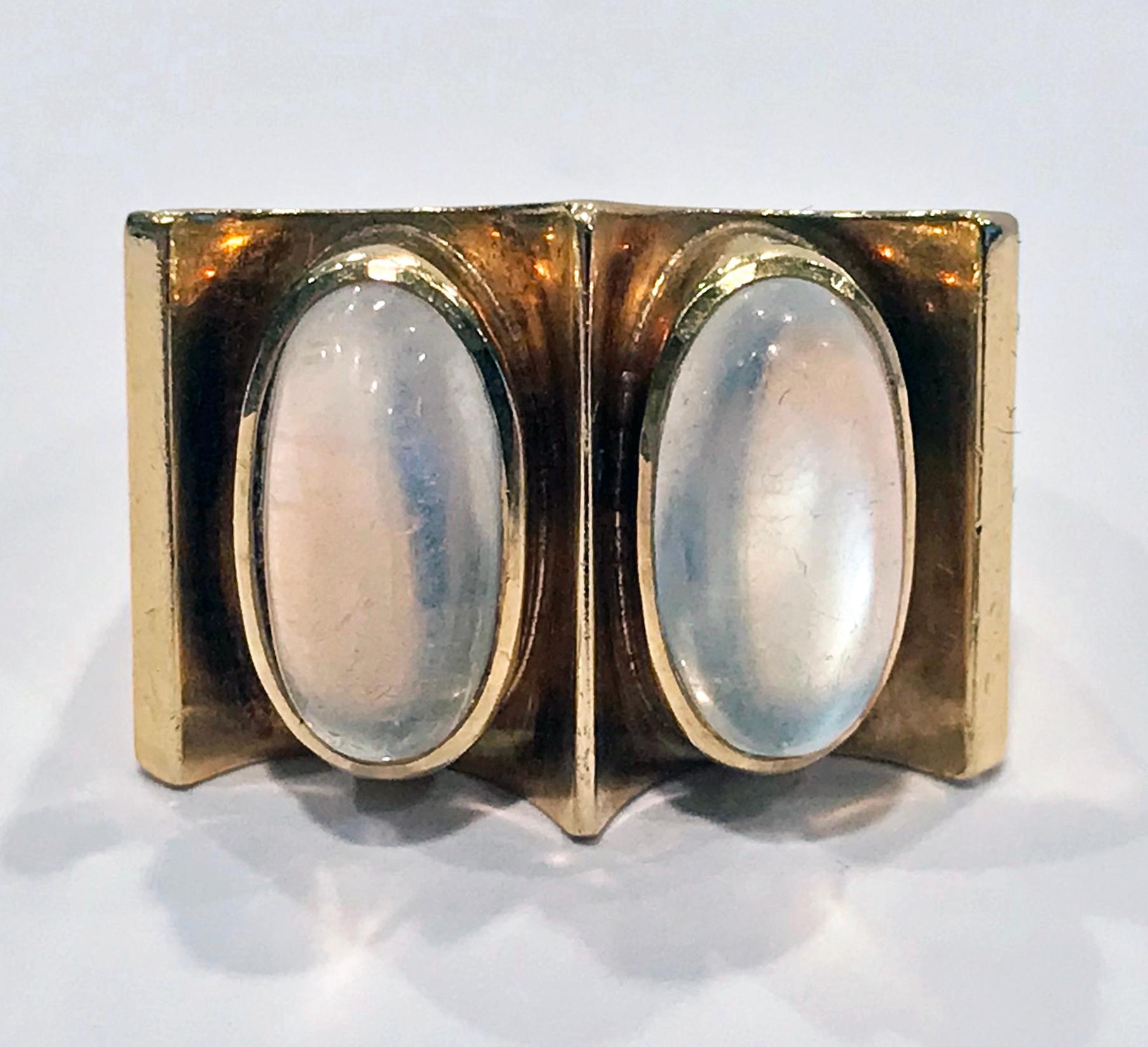 18K Moonstone Abstract Ring 1970’s. The Ring bezel set with two oval cabochon moonstones set side by side each within a groove like quadrilateral setting, plain tapered mount. Stamped 750 on interior of shank. Top measures approximately 17 x 23 mm.