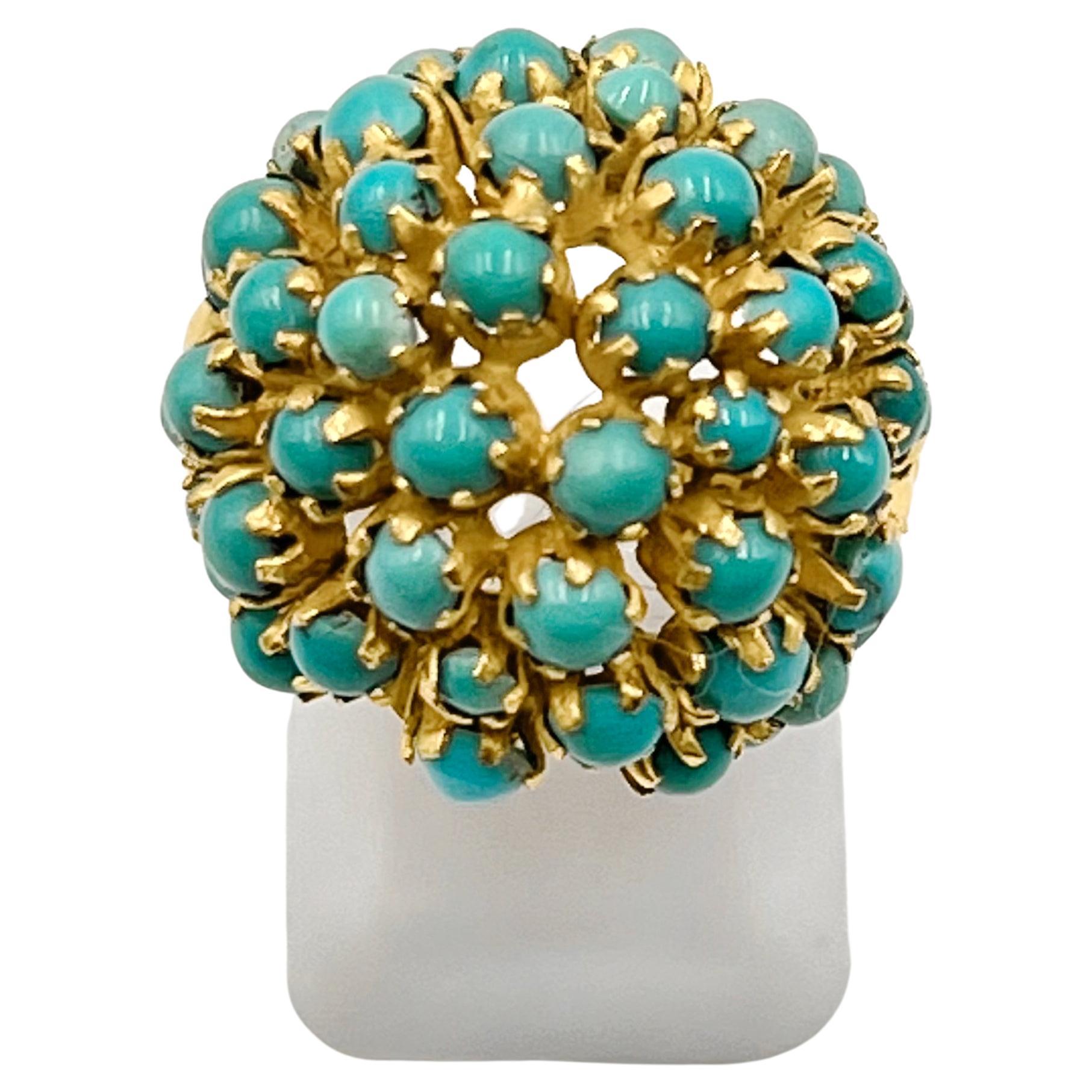 1970s domed cocktail ring, set with cabochon-cut natural turquoise in 18k yellow gold.  Open-work mounting featuring forty-eight 2.25-3.5mm circular cabochon-cut, natural turquoise stones.  Blue to greenish-Blue colors.  Polished button accent with