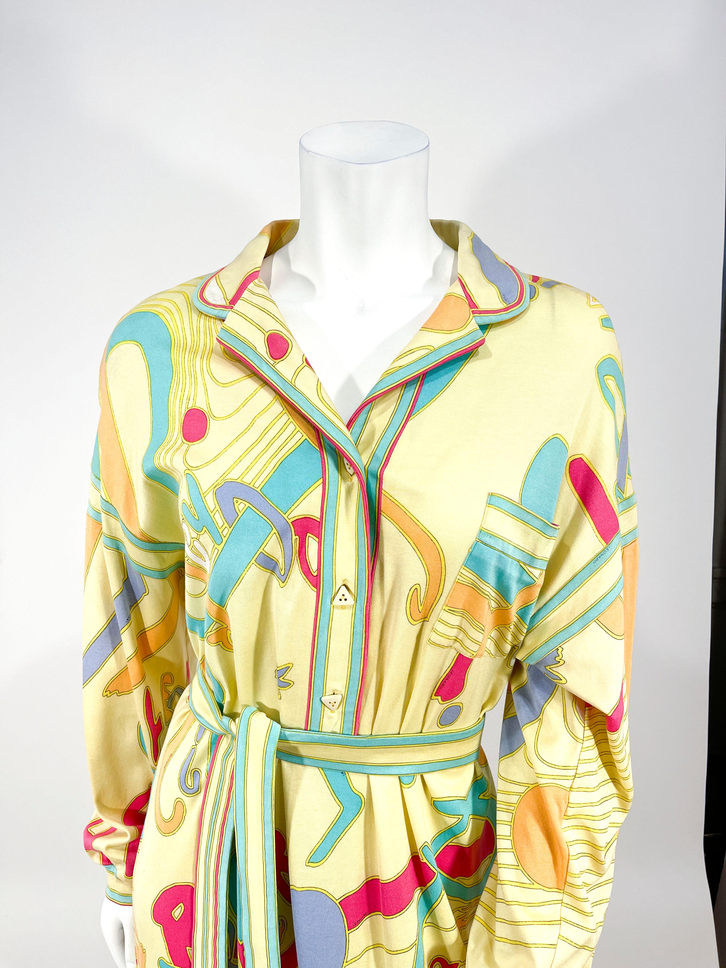 Late 1970s to early 1980s Leonard printed jersey dress. the print features pastels on shades of yellow with a typography motif. The silhouette features a button up neckline with speciality buttons, full cuffed sleeves, light shoulder padding, and a