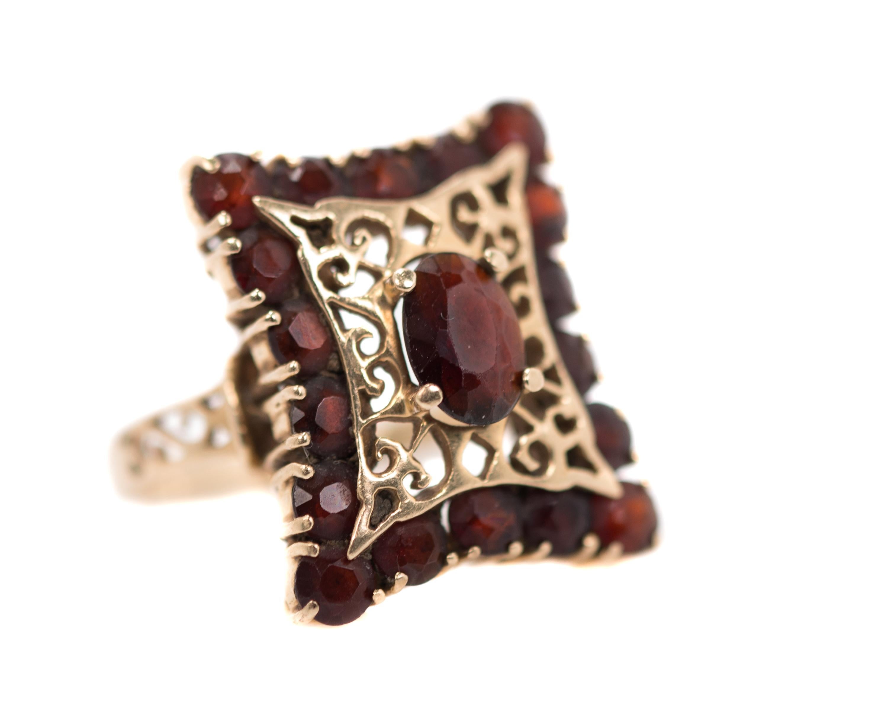 1971 Garnet Ring - 14 Karat Yellow Gold, Garnets

Features:
Originally purchased in South Africa
2.0 carats Garnets
Oval, faceted, 4-prong set Center Stone
16 stone halo
14 Karat Yellow Gold Setting
Decorative, Open Gallery
Filigree on face and