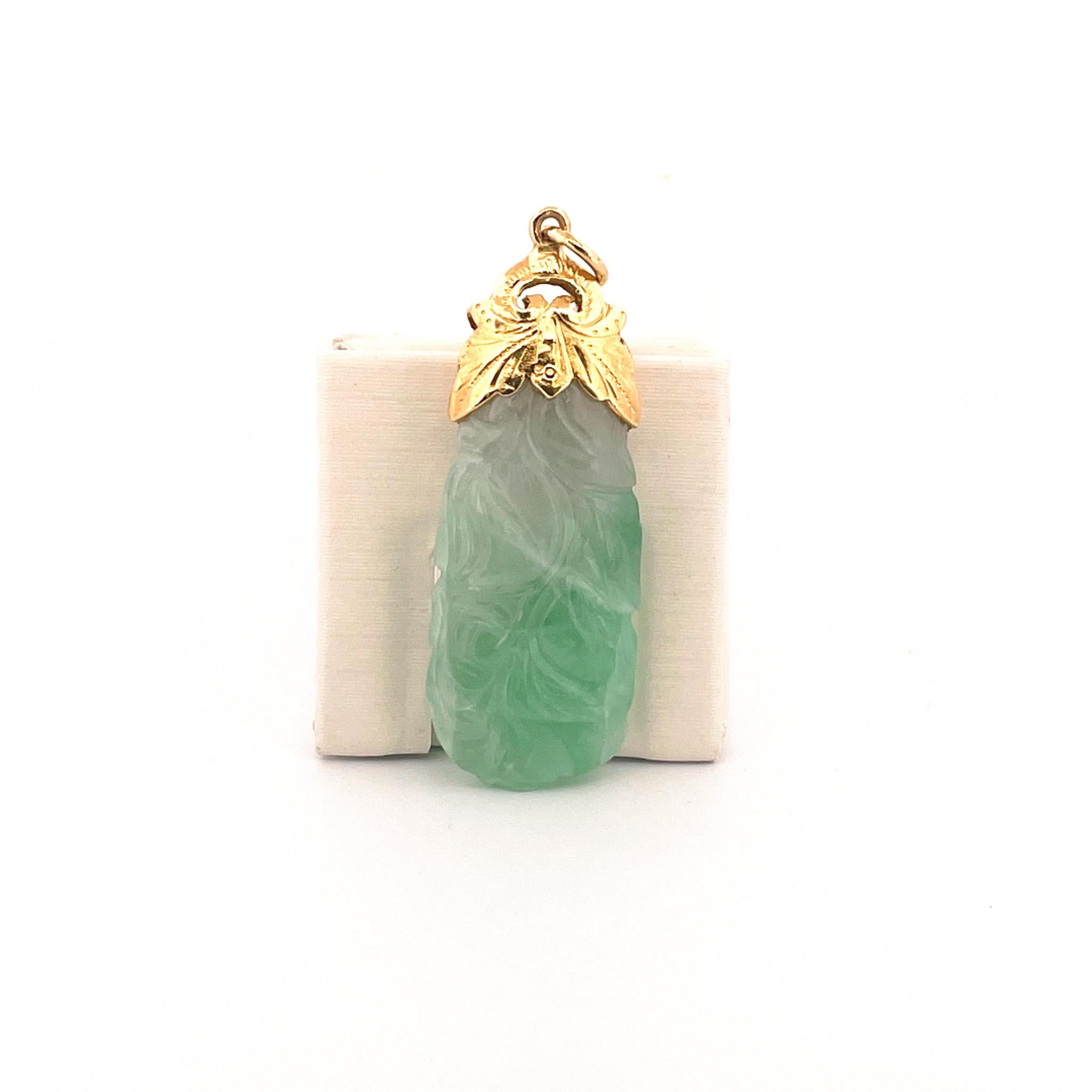 From the Eiseman Estate Jewelry Collection, circa 1970s, 24 karat yellow gold pendant featuring carved green jadeite. This pendant is crafted with a textured yellow bail and measures 54 x 18.35 x 7.14 mm.