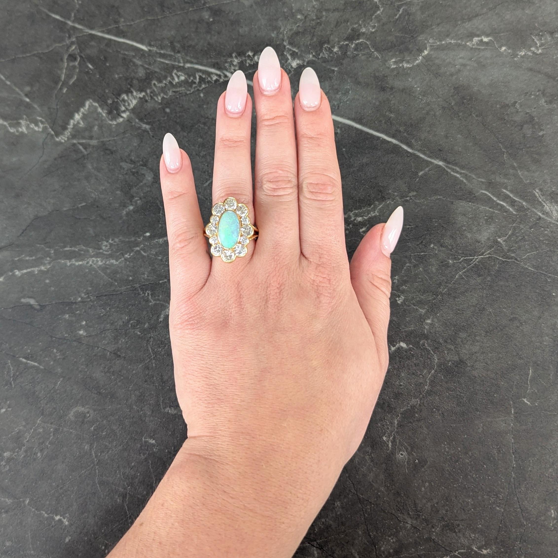 Centering an elongated oval shaped opal cabochon measuring 8.0 x 15.0 mm
White in body color with spectral play-of-color - bezel set with halo surround
Comprised of transitional cut diamonds bead set in semi-bezels
Weighing approximately 4.50 carats
