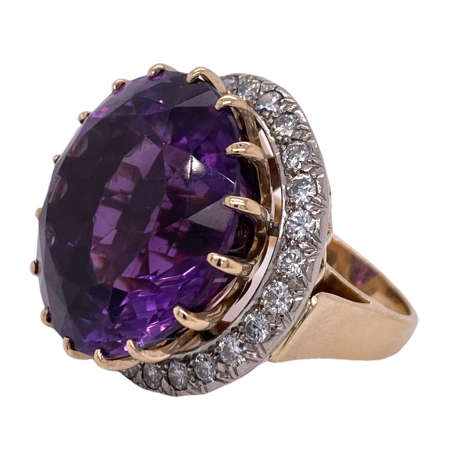 Stunning vintage cocktail ring fashioned in 14 karat yellow gold. The ring features an approximately 52 carat round amethyst gemstone with an under halo of 26 round brilliant cut diamonds weighing approximately 2.50 carat total weight. The diamonds