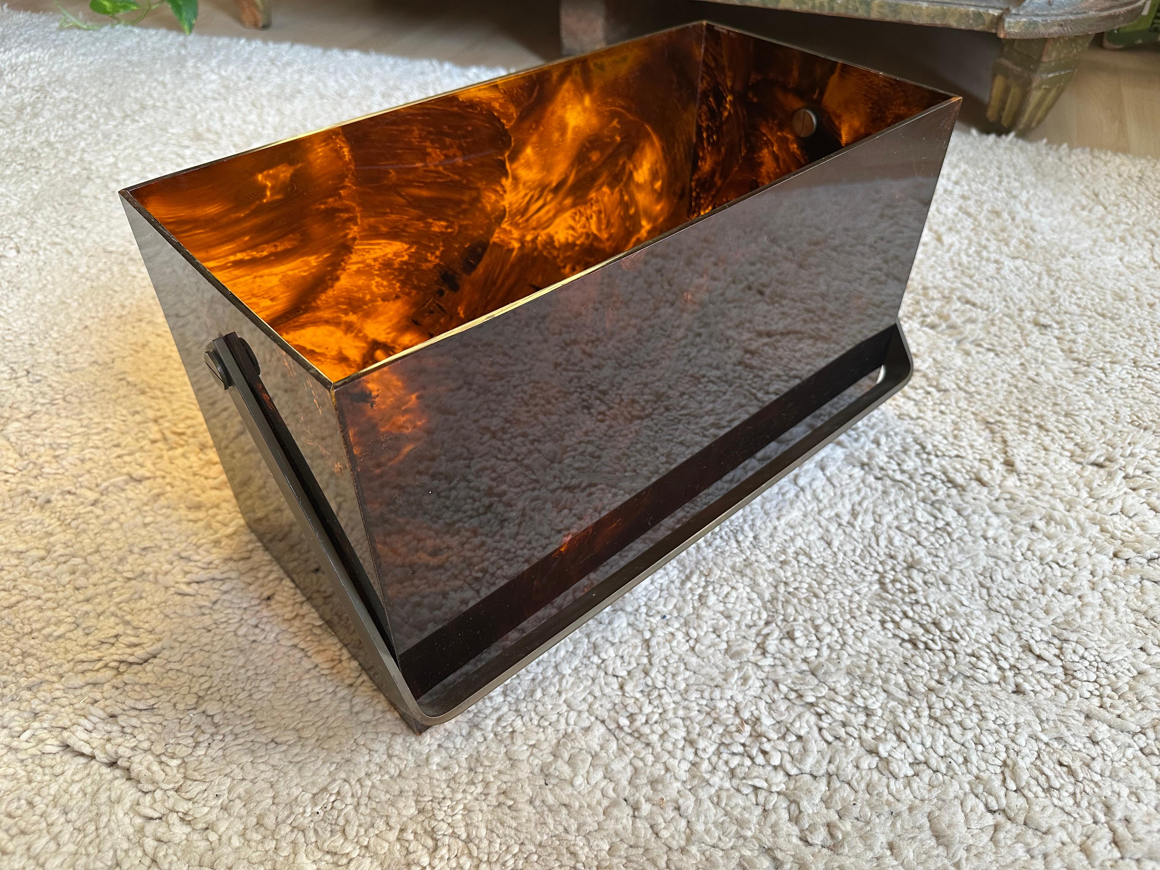 Cette élégante boîte à revues rectangulaire en acrylique des années 1970 est un exemple frappant du design du milieu du siècle. Dotée d'une solide poignée en laiton poli et réalisée dans le style très recherché de la fausse écaille, cette pièce