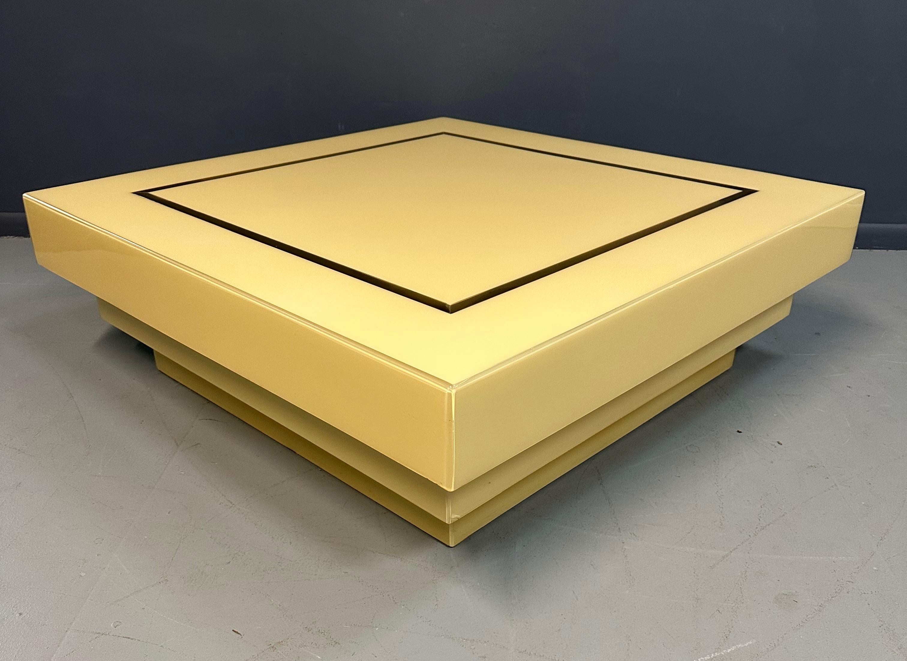 This stunning 1970s coffee table showcases eye-catching design with its stepped cream acrylic body and brass ribbon inlay. Create a unique look in your home with this stylish piece of mid-century modern design. The lovely serene color of this table