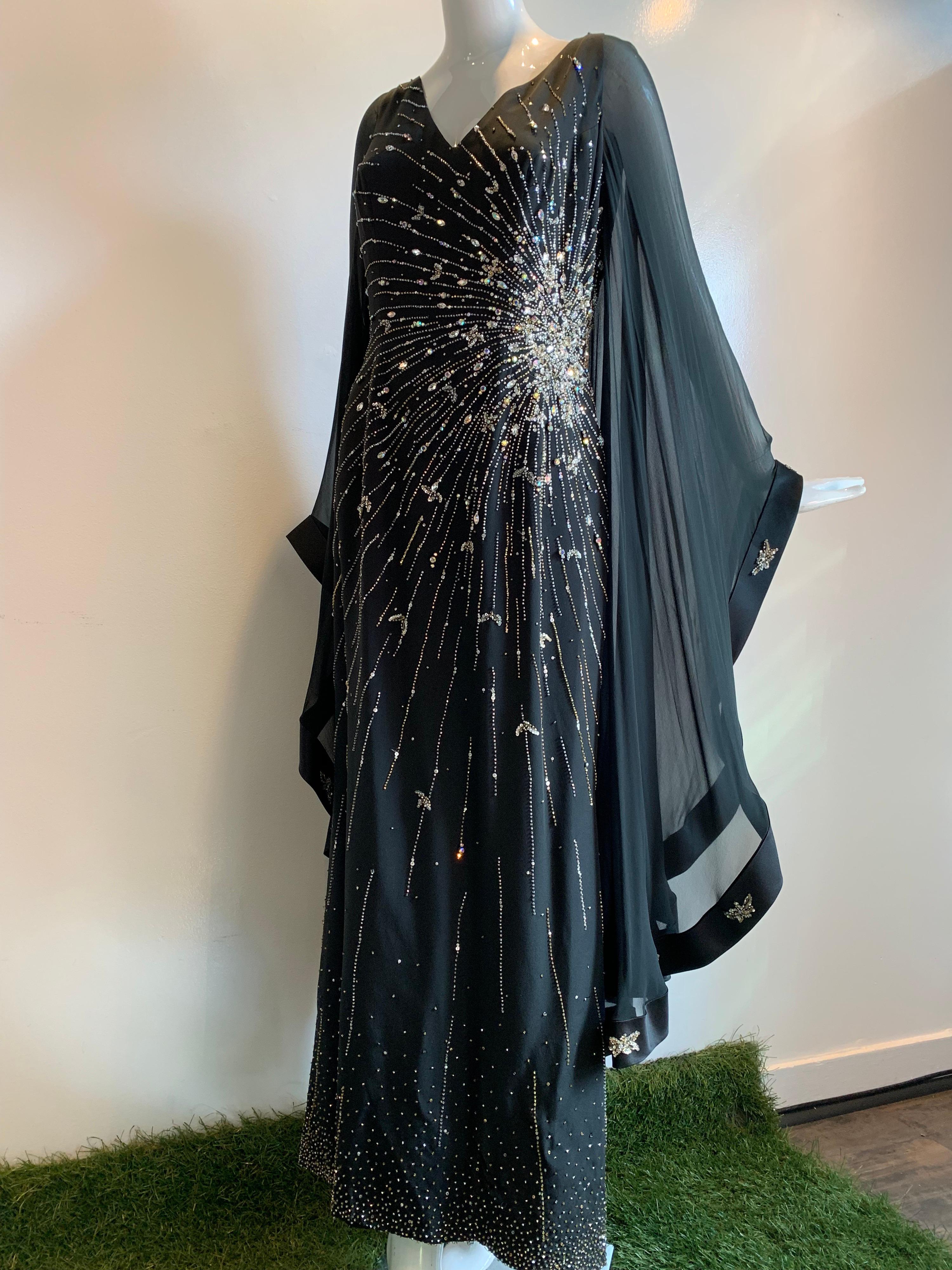A spectacular 1970s Alan Cherry black silk chiffon Goddess-style evening gown with a huge starburst of star-shine across the body from hip to bust in beadwork and rhinestones.  Sleeves are angel-wing style edged in silk satin with beaded medallions. 