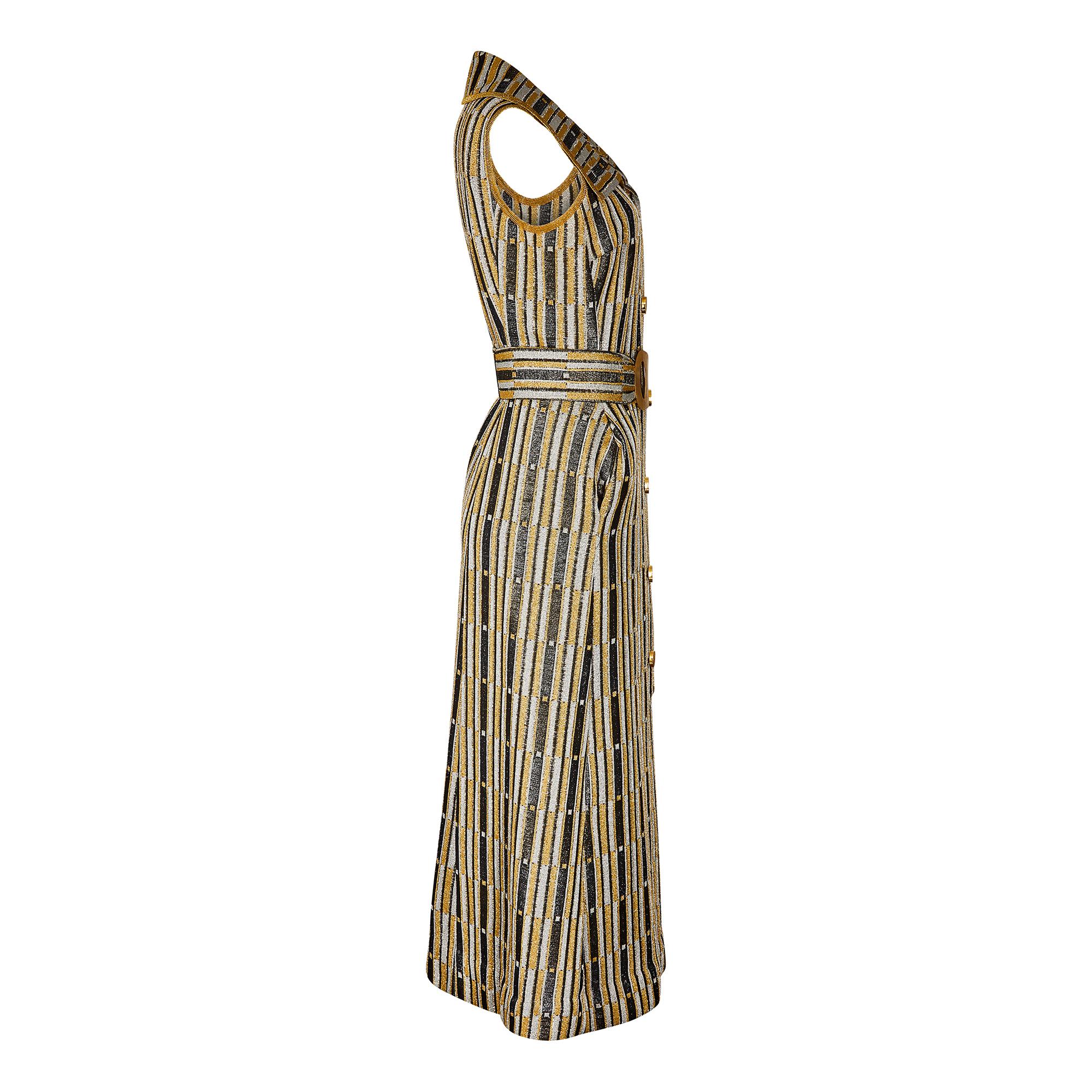 Very striking 1970s couture made Art Deco inspired dress made from a metallic lame knit knit in a gold, silver and black geometric block print. The dress has a wide straight collar, is sleeveless and front fastening. The button stand hosts some